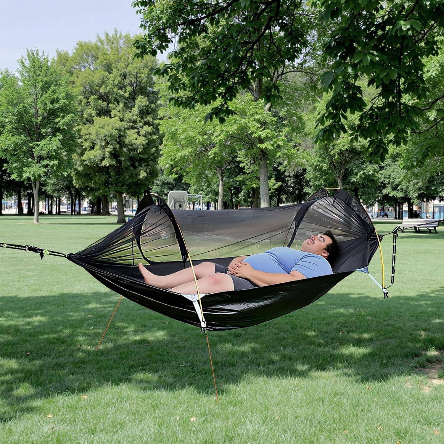 Eine Person entspannt sich in einer Hängematte unter belaubten Bäumen in einem Park und vermittelt eine friedliche, gemächliche Atmosphäre an einem sonnigen Tag.