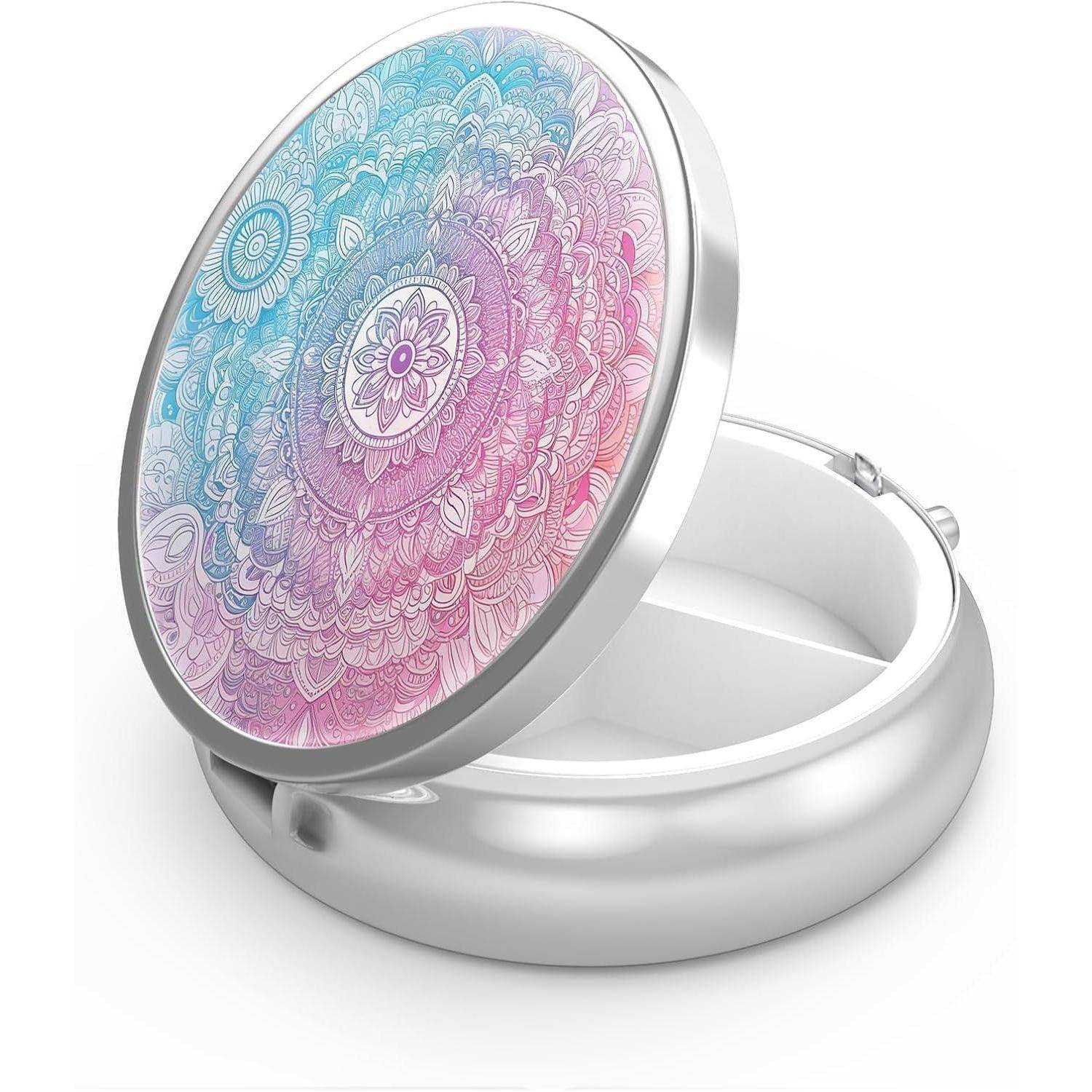 Eine runde, silberne Pillendose mit einem kunstvollen Mandala-Motiv in Rosa und Blau auf dem Deckel, geöffnet, sodass zwei Fächer im Inneren sichtbar sind.