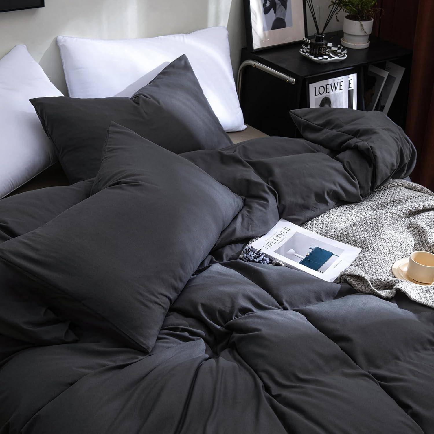 Eine gemütliche Schlafzimmerszene mit einem ordentlich bezogenen, dunkelgrauen Bett, weißen Kissen, einer Zeitschrift auf dem Bett und einem kleinen Couchtisch daneben.