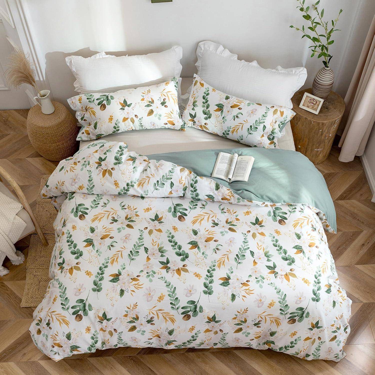 Bett mit blumenmusterbedeckten Laken und Kissen in Grün- und Orangetönen. Ein Buch liegt aufgeschlagen auf dem Bett. Sonnenlicht strömt durch das Fenster.