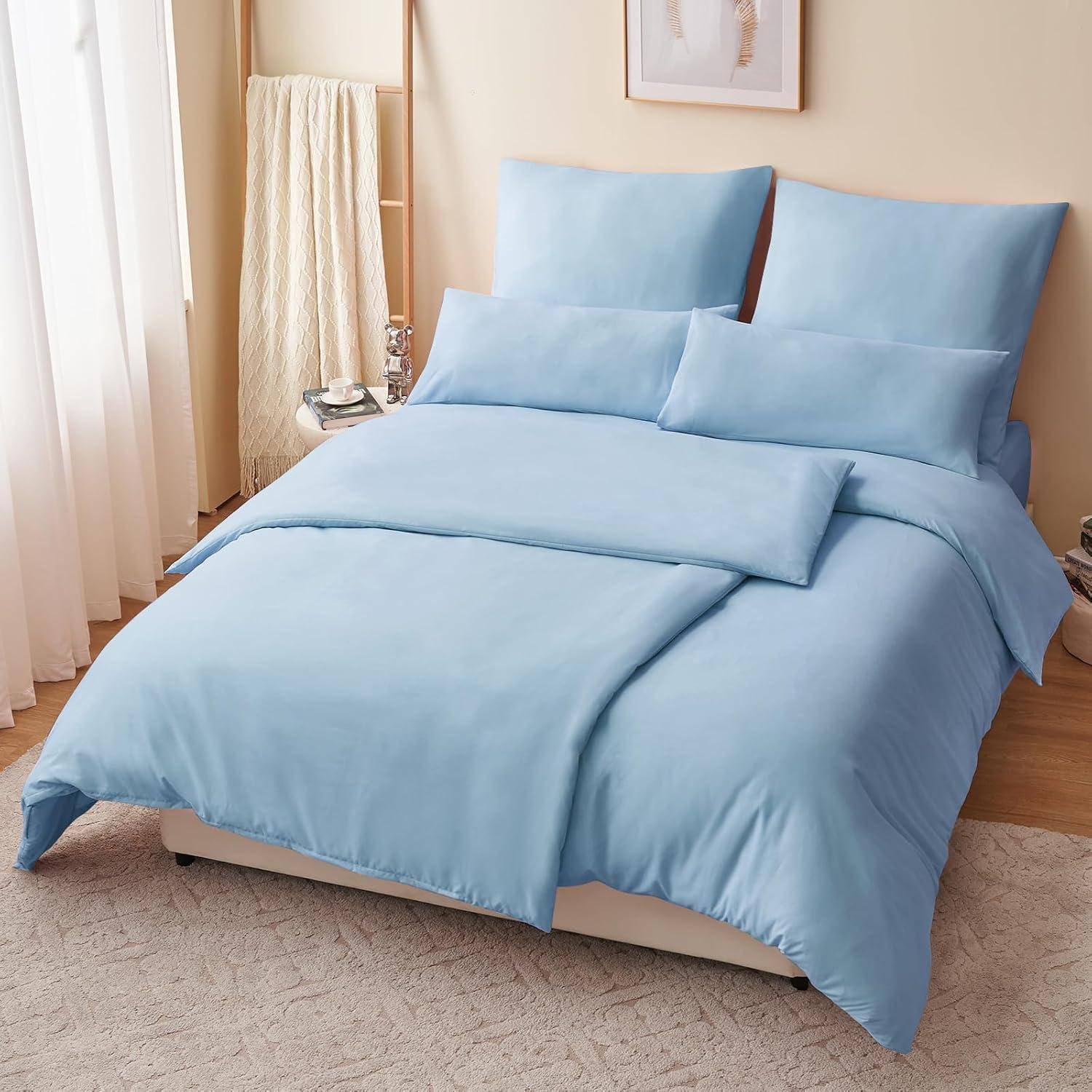 Ein ordentlich gemachtes Bett mit hellblauer Bettwäsche in einem warmbeleuchteten Schlafzimmer, mit einer Holzleiter, auf der eine Decke drapiert ist, und gerahmter Wandkunst.