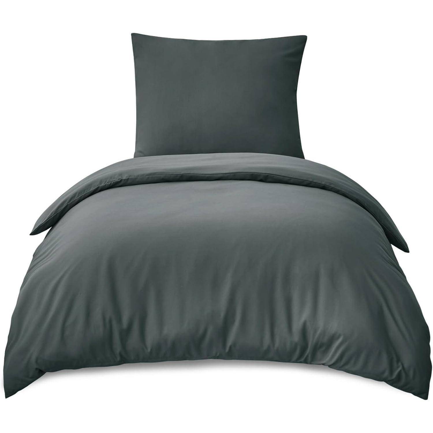 Ein ordentlich gemachtes Bett mit einem dunkelgrauen Bettdecken und passenden Kissen, das eine einfache und moderne Schlafzimmeratmosphäre präsentiert.