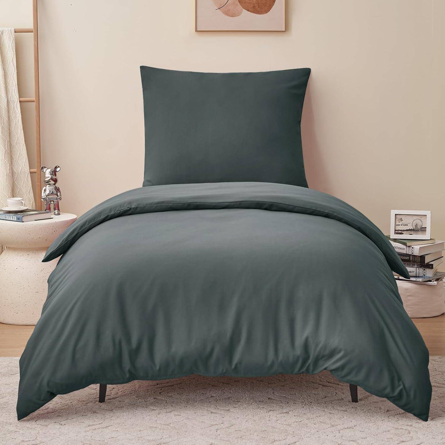 Ein aufgeräumtes Schlafzimmer zeigt ein Bett mit dunkeltürkiser Bettwäsche. In der Nähe hält ein kleiner Tisch eine Tasse und ein Buch, und minimalistische Dekoration verstärkt die ruhige Atmosphäre des Raumes.