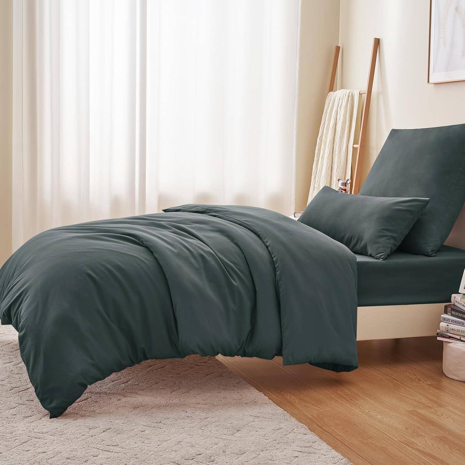 Ein ordentlich gemachtes Bett mit dunkelgrüner Bettwäsche in einem minimalistischen Schlafzimmer. Ein Kissen und eine zusammengelegte Decke verleihen eine gemütliche Atmosphäre.