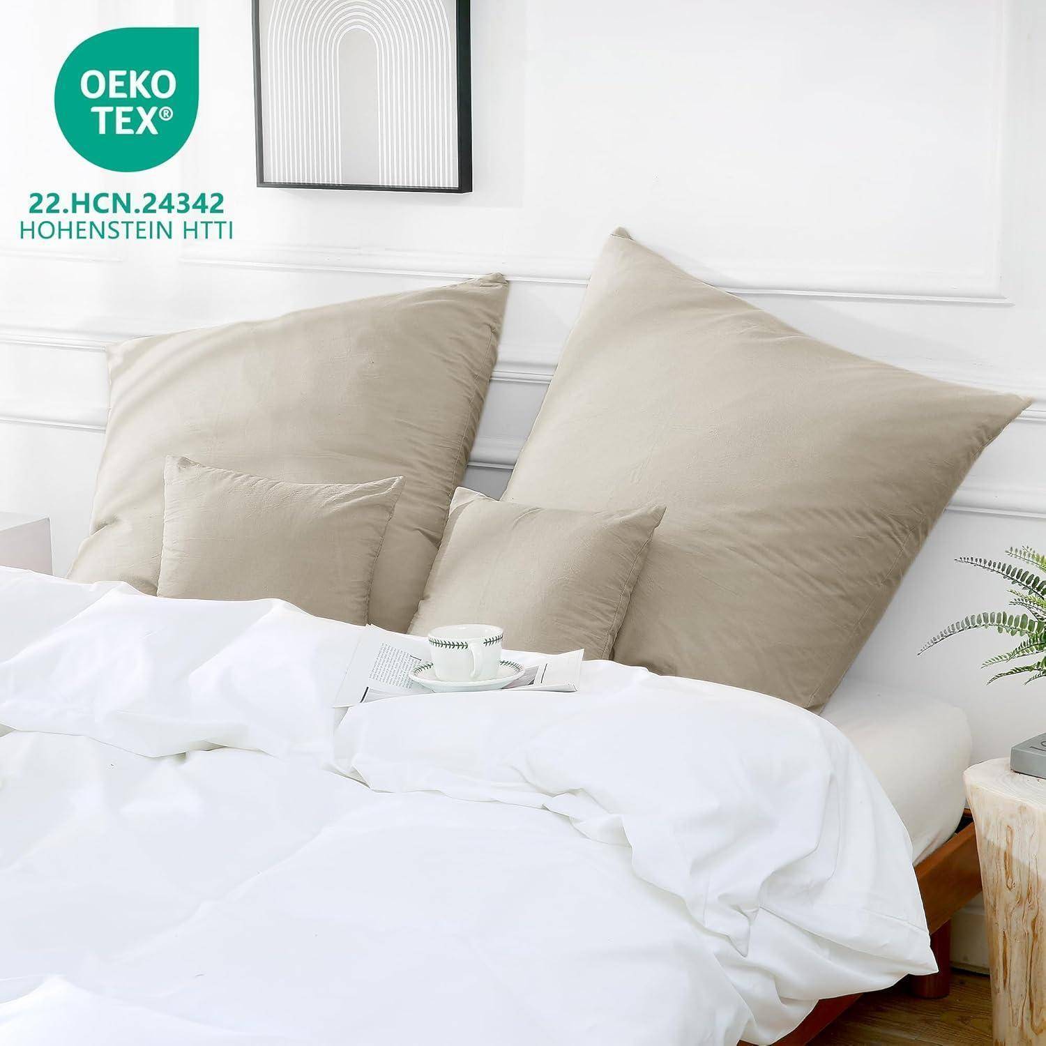 Eine gemütliche Schlafzimmerszene mit einem ungemachten Bett, das mit beigen Kissen und einem weichen weißen Bettdecke ausgestattet ist. Das OEKO-TEX-Logo weist auf zertifizierte Textilien hin.
