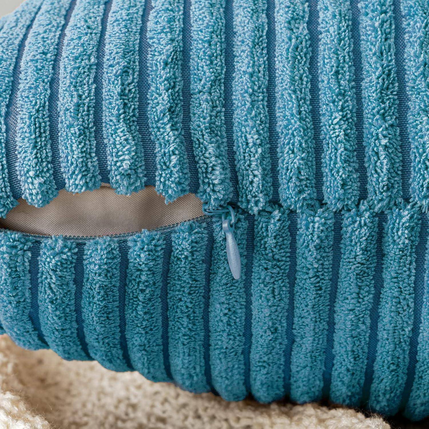 Ein strukturiertes blaues Kissen mit vertikalen Streifen, das einen Reißverschluss entlang einer Kante aufweist. Das Kissen ruht auf einer beigen, flauschigen Oberfläche.