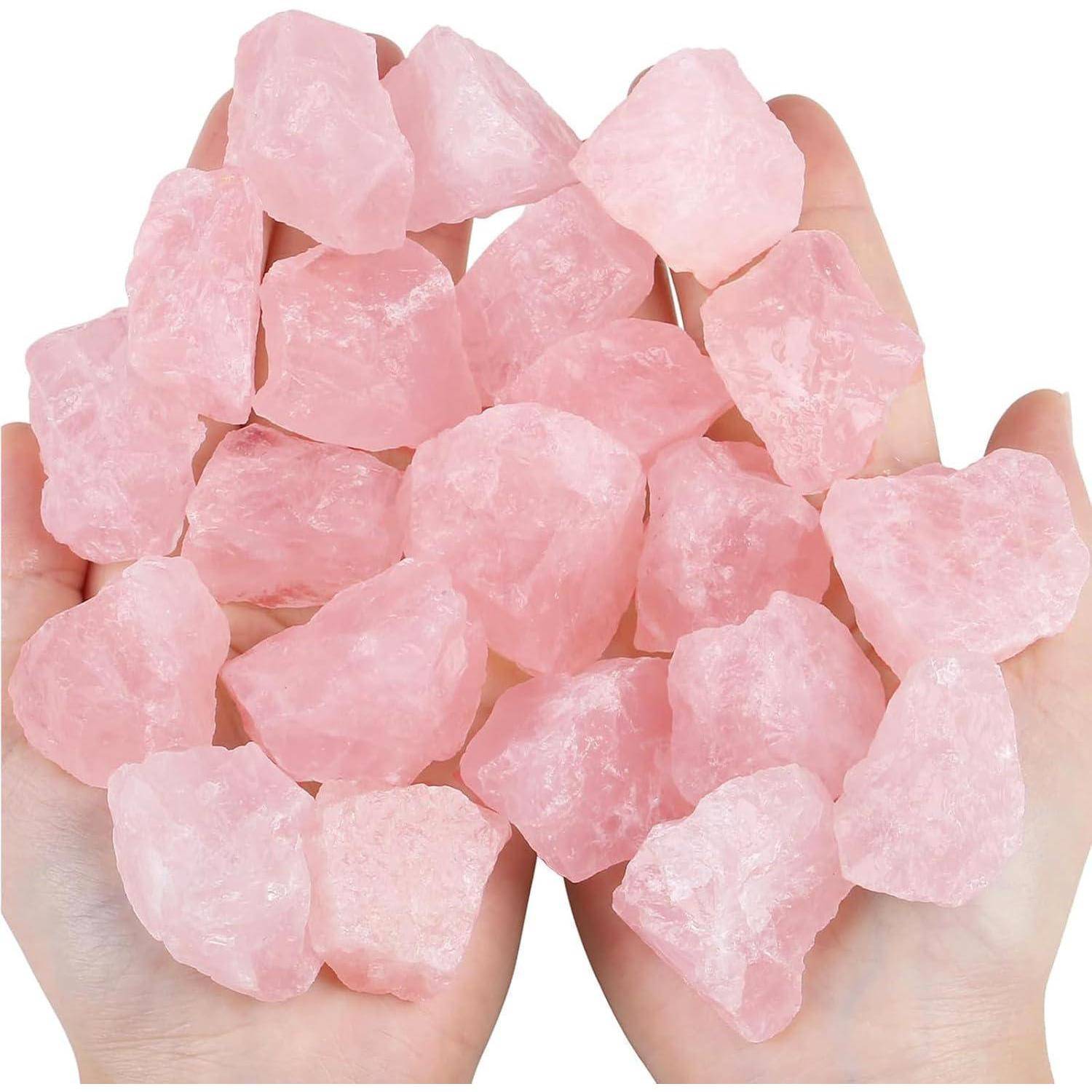 Zwei Hände, die mehrere rohe, rosa Rosenquarz-Steine halten.