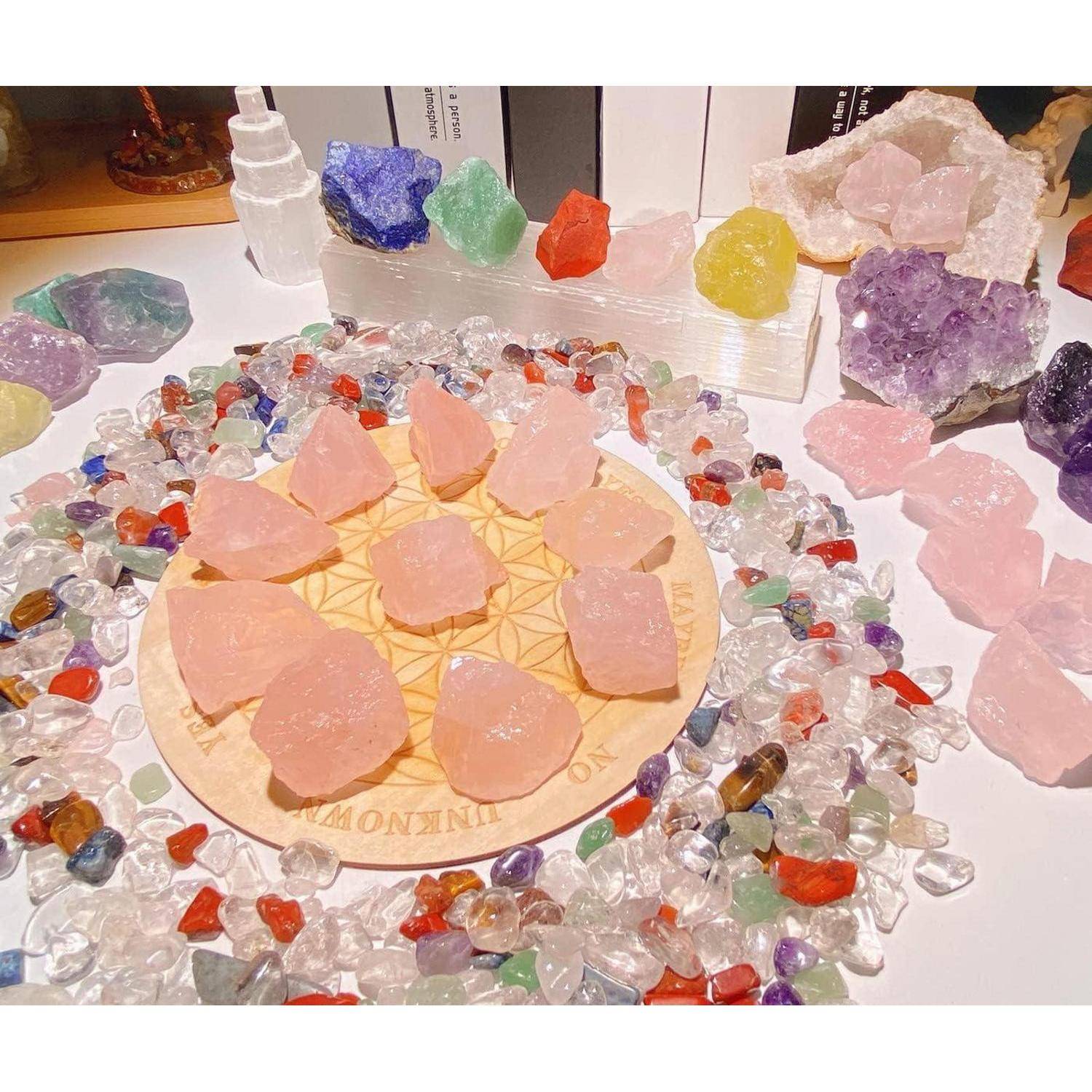 Eine Vielzahl von farbigen Kristallen, die in einem Kreis auf einer gemusterten Oberfläche angeordnet sind und Rosenquarz, durchsichtige Steine und Amethyste umfassen.