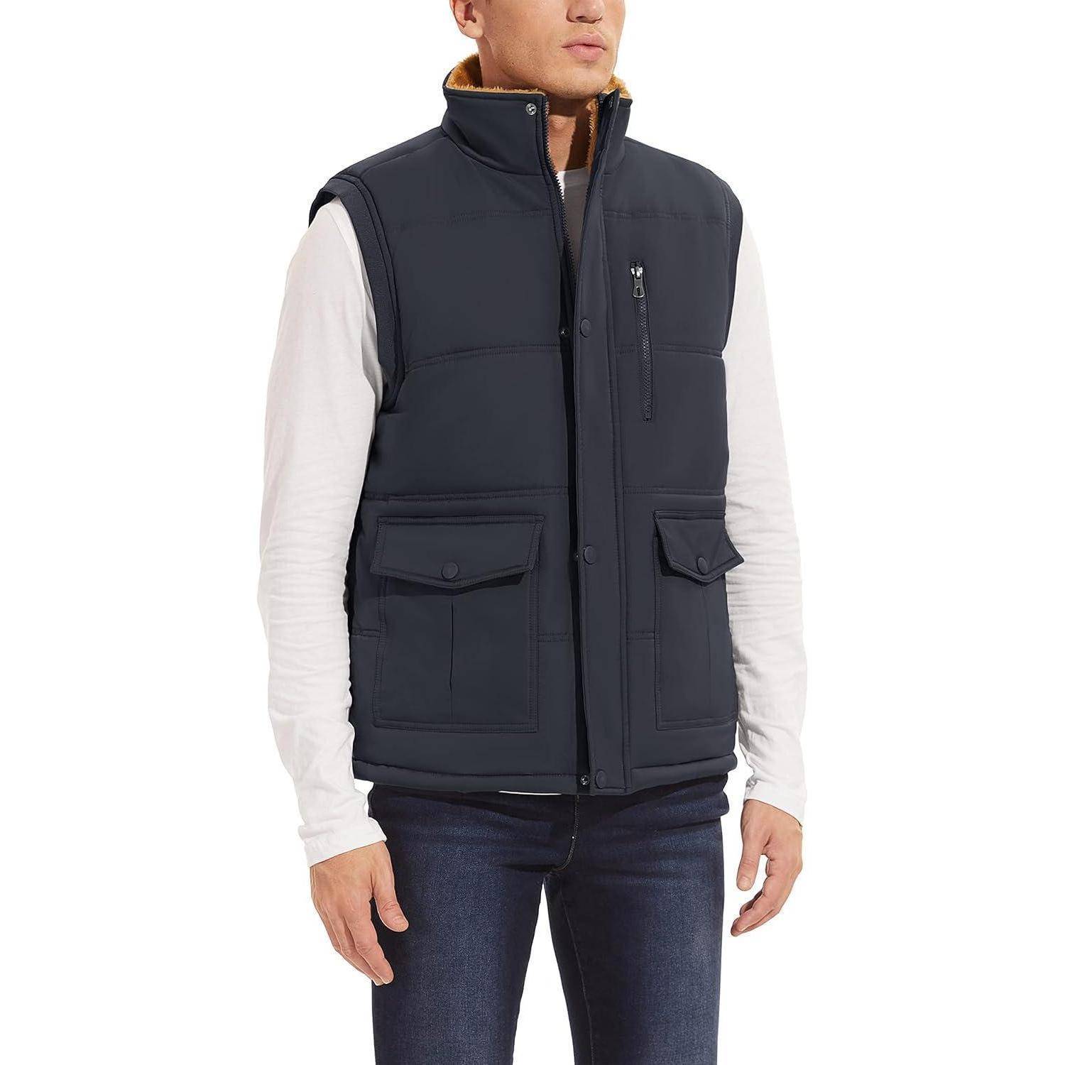 Eine Person, die eine dunkle, gepolsterte Weste über einem weißen Langarmshirt und Jeans trägt und lässig steht.