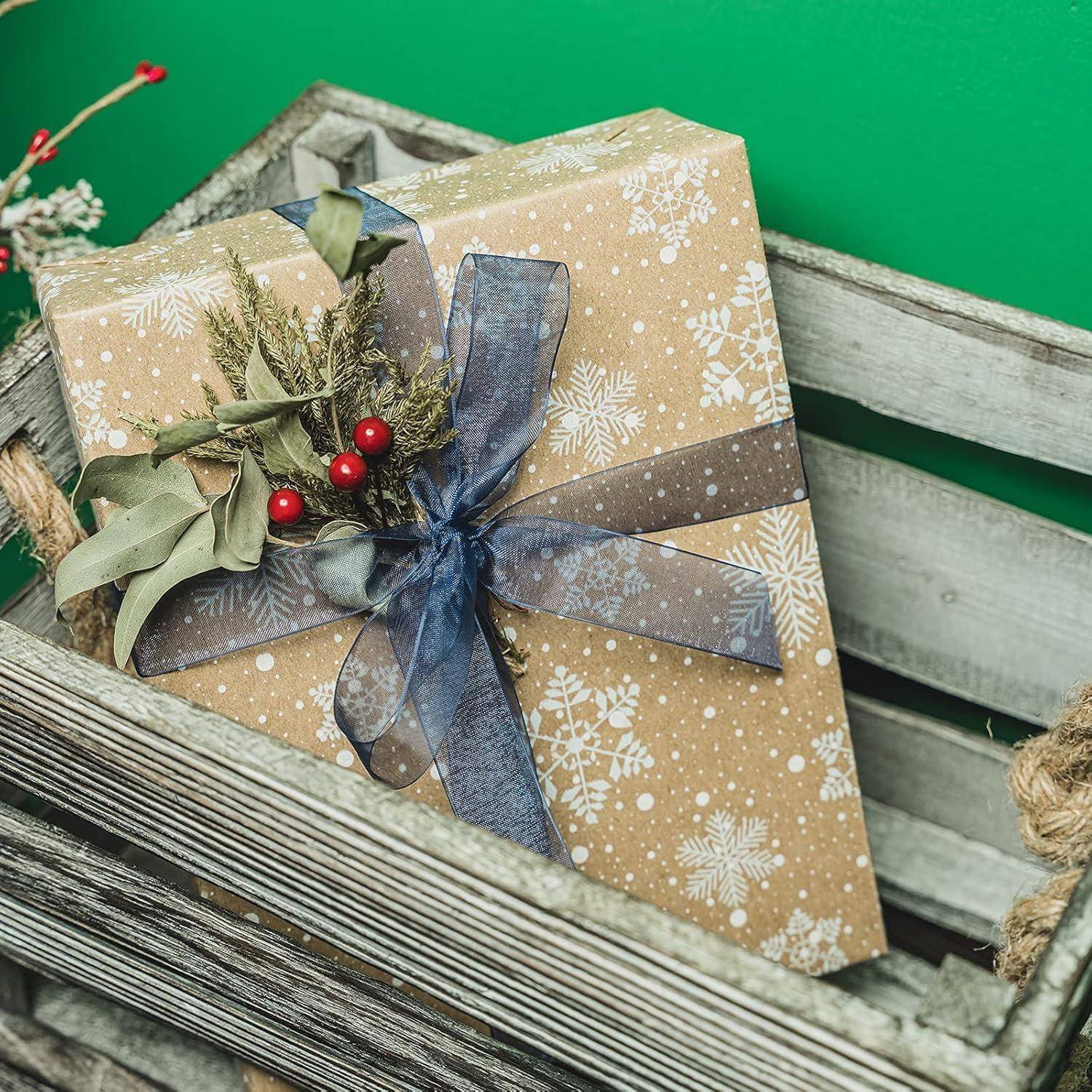 Ein in Schneeflocken-Geschenkpapier eingepacktes Geschenk mit blauen und grünen Bändern, dekoriert mit Grünzeug und roten Beeren, in einer rustikalen Holzkiste platziert.