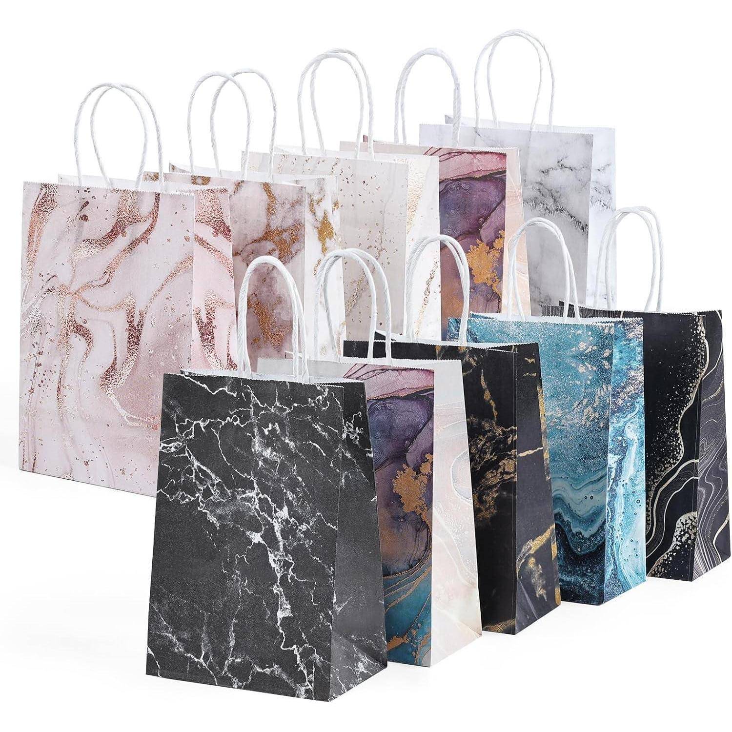 Eine Gruppe von acht Geschenktüten mit verschiedenen Marmor- und abstrakten Designs, die jeweils weiße Griffe haben und in Reihen angeordnet sind.