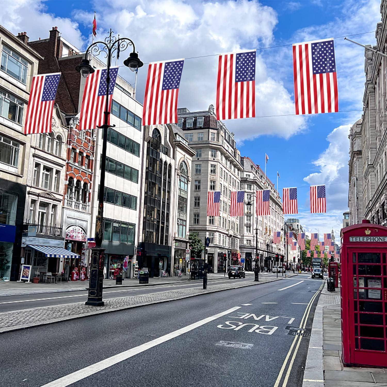 Eine belebte Stadtstraße, geschmückt mit zahlreichen amerikanischen Flaggen auf beiden Seiten, mit historischen Gebäuden und einer traditionellen roten Telefonzelle.