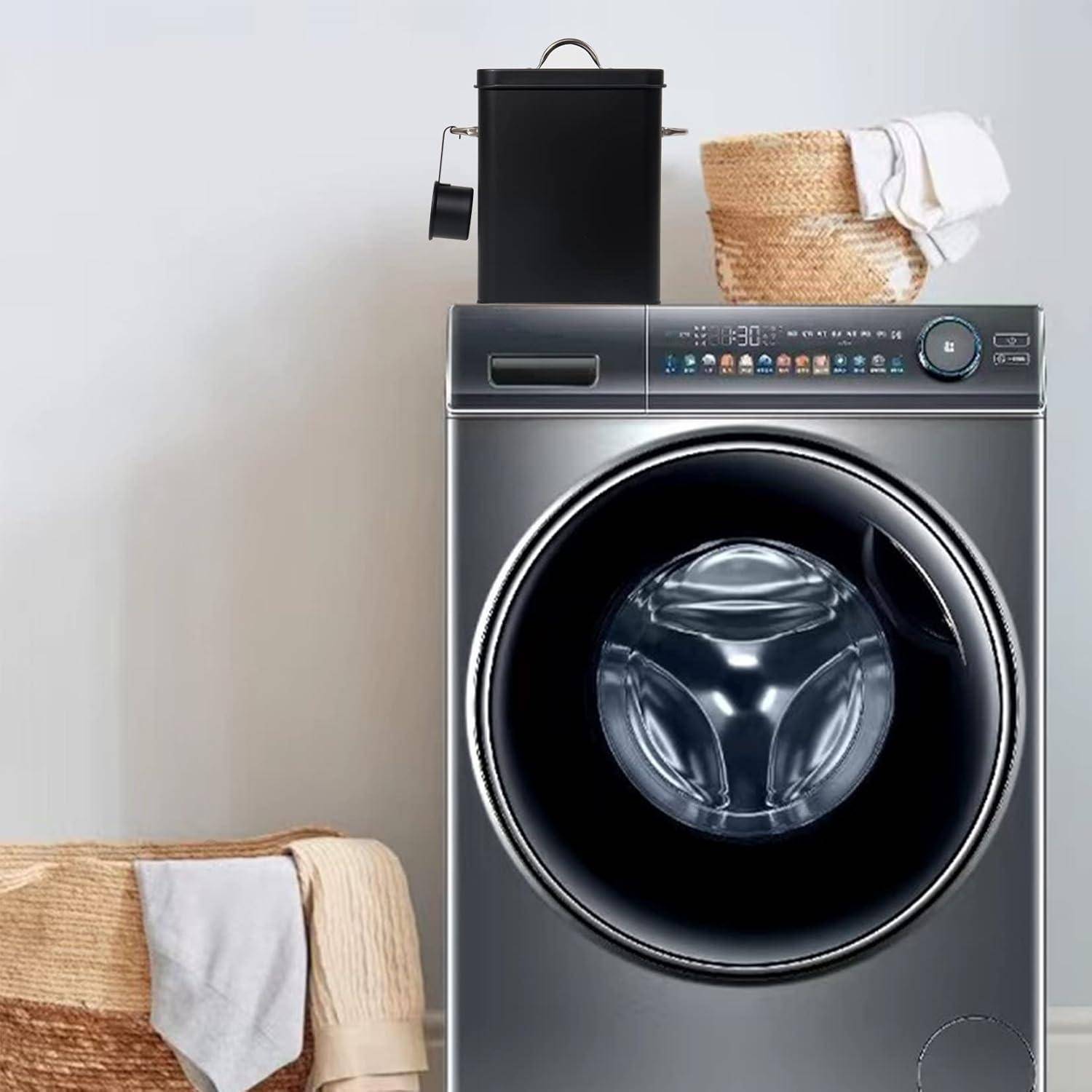 Eine moderne Frontlader-Waschmaschine steht in einem Waschraum, mit einem Stapel zusammengelegter Handtücher oben drauf und einem Wäschekorb in der Nähe.
