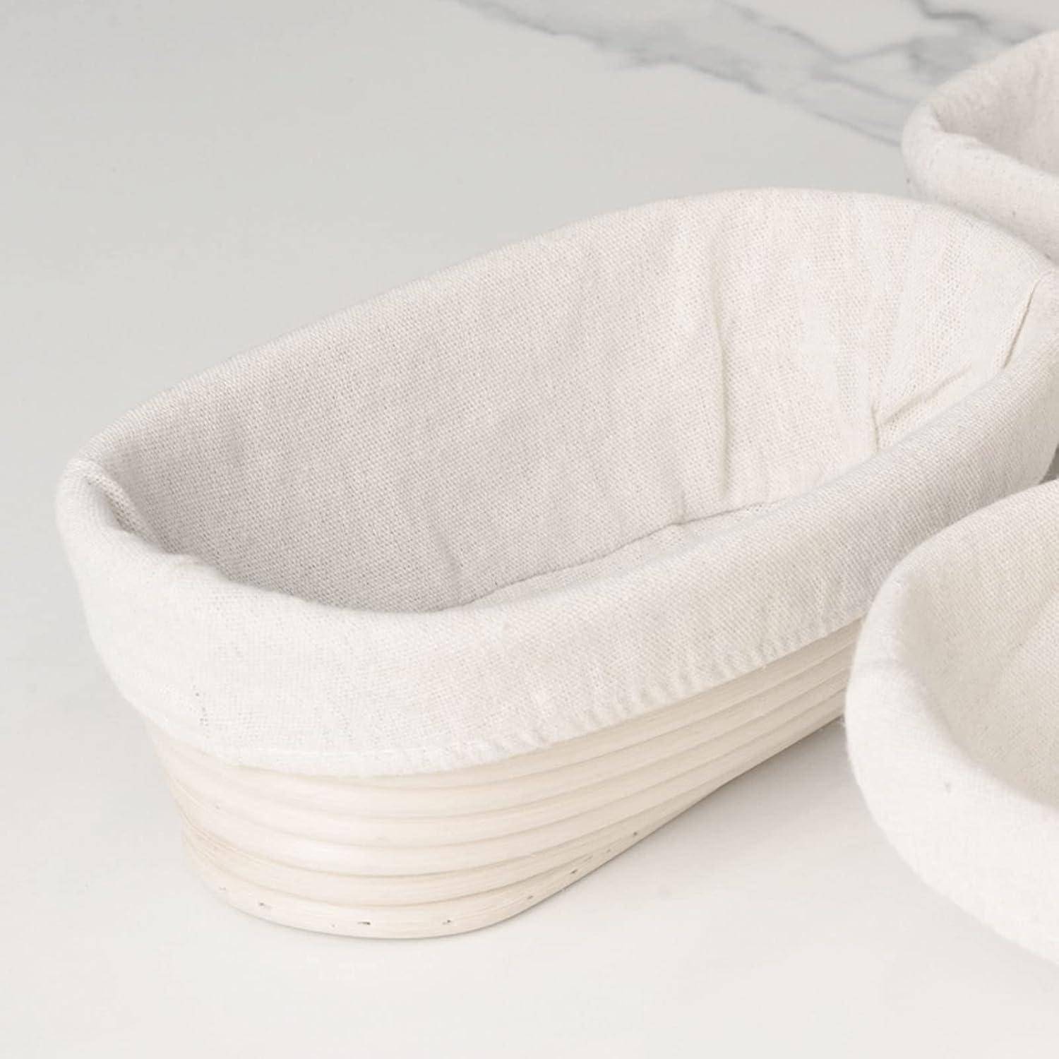 Ein Paar weiß ausgeschlagene Brotaufgangskörbe mit gerillten Außenseiten, die auf einer hellen Marmoroberfläche stehen.