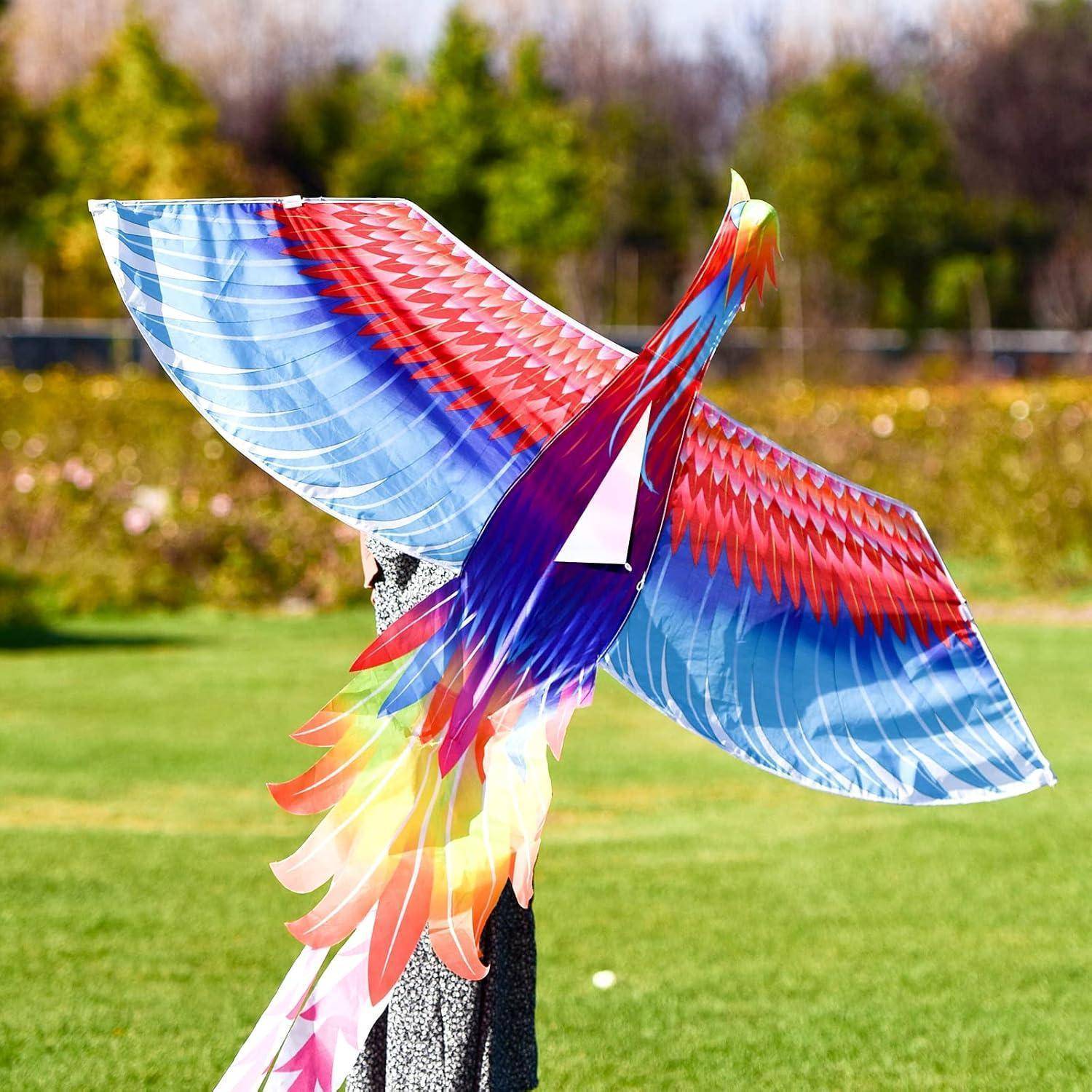 Eine farbenprächtige Drachen in Vogelform mit lebhaft blauen, roten und pinken Federn fliegt vor einer Kulisse aus grünen Bäumen und Gras.