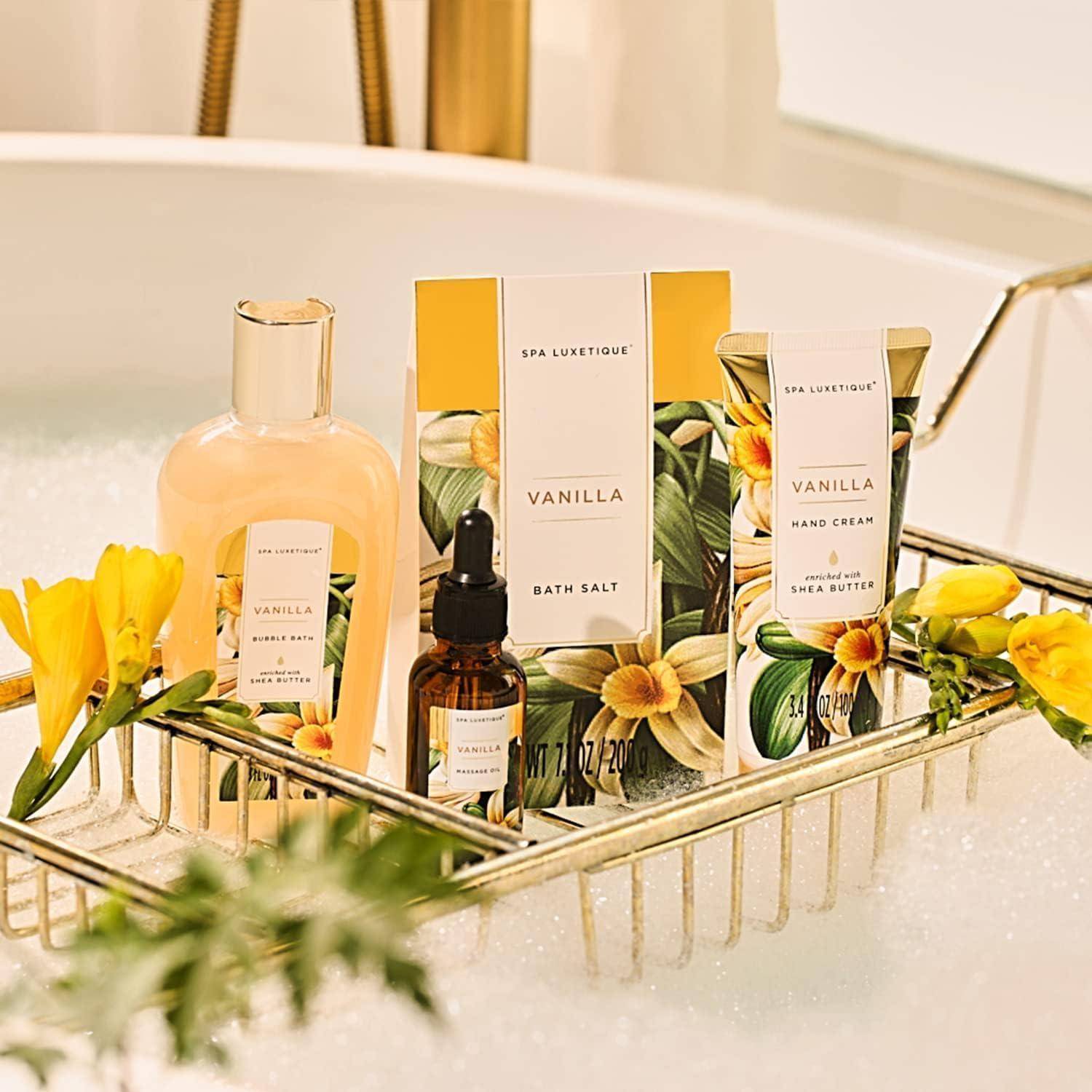 Vanille-duftender Spa-Set mit Bademilch, Badesalz und Handcreme, auf einem Badewannentablett präsentiert, umgeben von gelben Blumen.