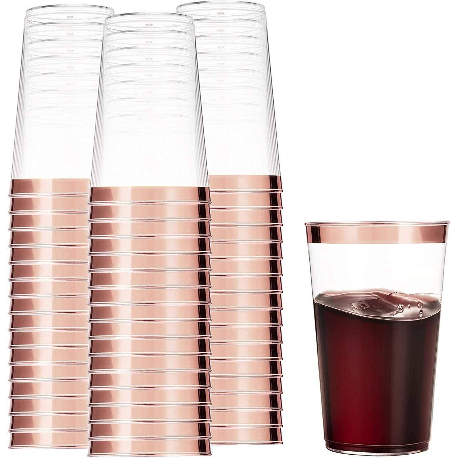 Gestapelte durchsichtige Plastikbecher mit roségoldenen Rändern neben einem einzelnen Becher, der mit dunkler Flüssigkeit gefüllt ist.