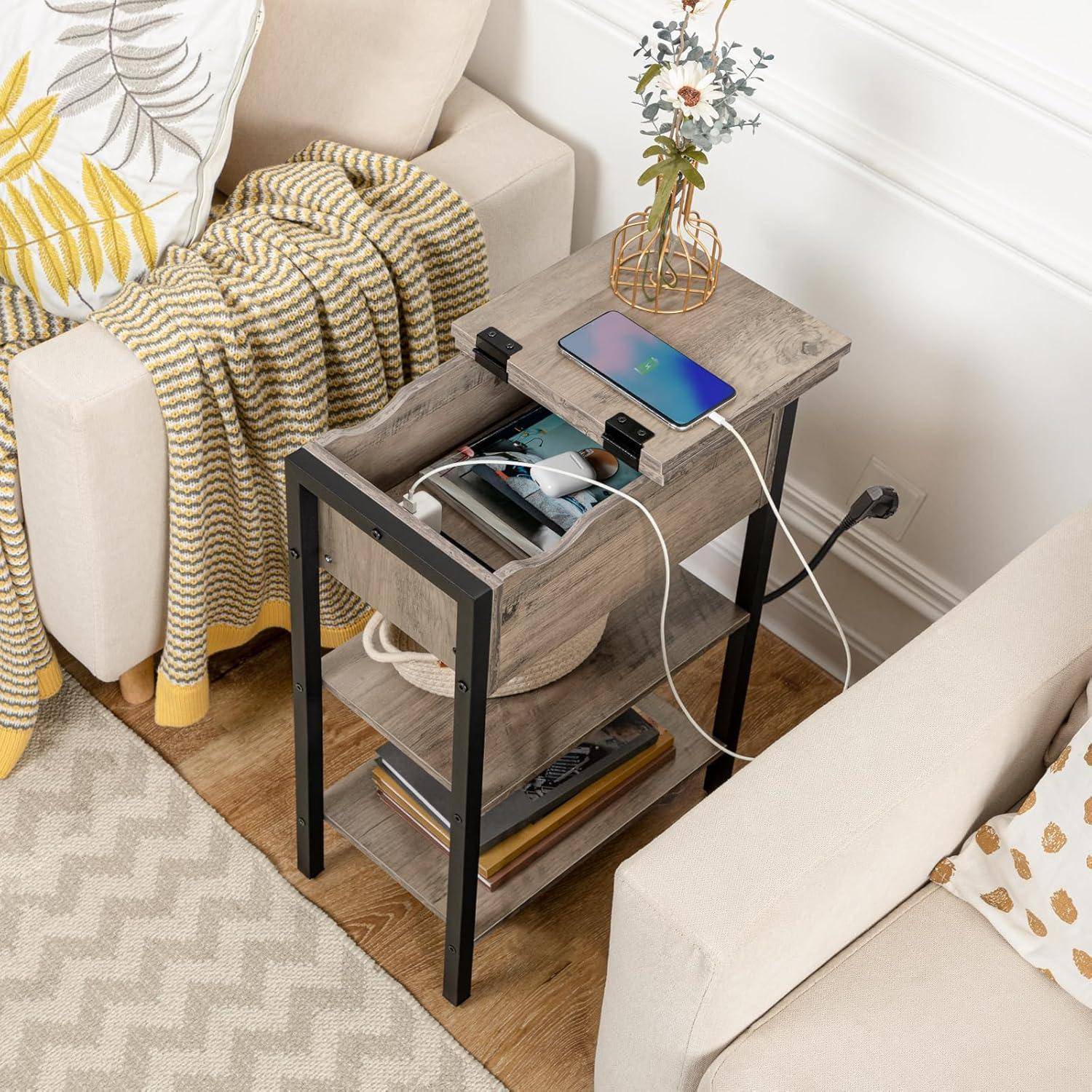 Ladestationen-Tisch mit mehreren elektronischen Geräten, Büchern und einer Blumenvase, der neben einem Sofa mit gemusterter Decke steht.