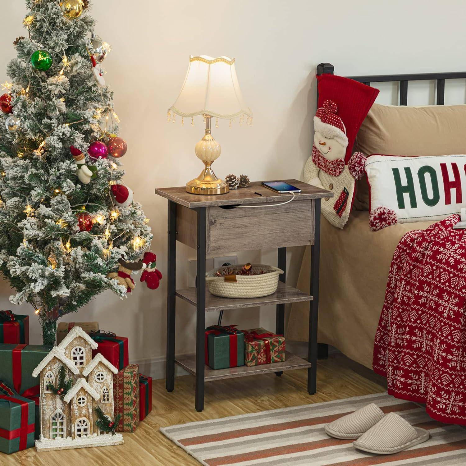 Ein gemütliches Weihnachts-Schlafzimmer mit einem dekorierten Baum, einem kleinen Tisch mit einer Lampe und einem Bett, das ein „Ho Ho Ho