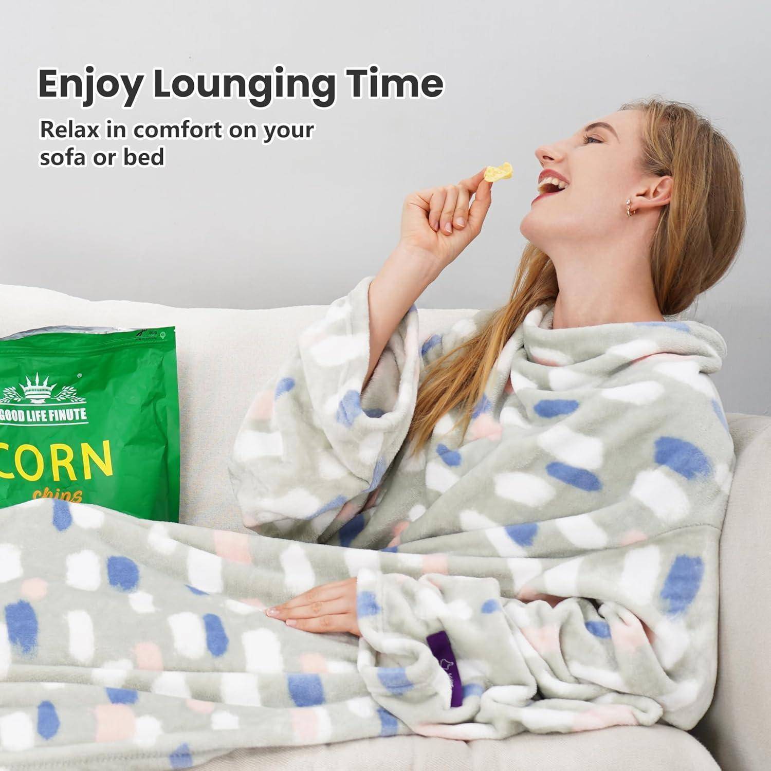 Eine Person entspannt sich auf einem Sofa, in eine gemusterte Decke gehüllt, und isst einen Snack. Text lautet: „Genieße deine Ruhezeit. Entspanne dich in Komfort auf deinem Sofa oder Bett.