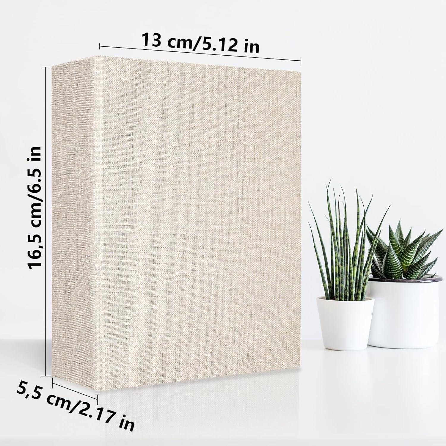 Ein beiger strukturierter Buchumschlag mit beschrifteten Maßen: 13 cm/5,12 Zoll Breite, 16,5 cm/6,5 Zoll Höhe, 5,5 cm/2,17 Zoll Tiefe, neben zwei Topfpflanzen.