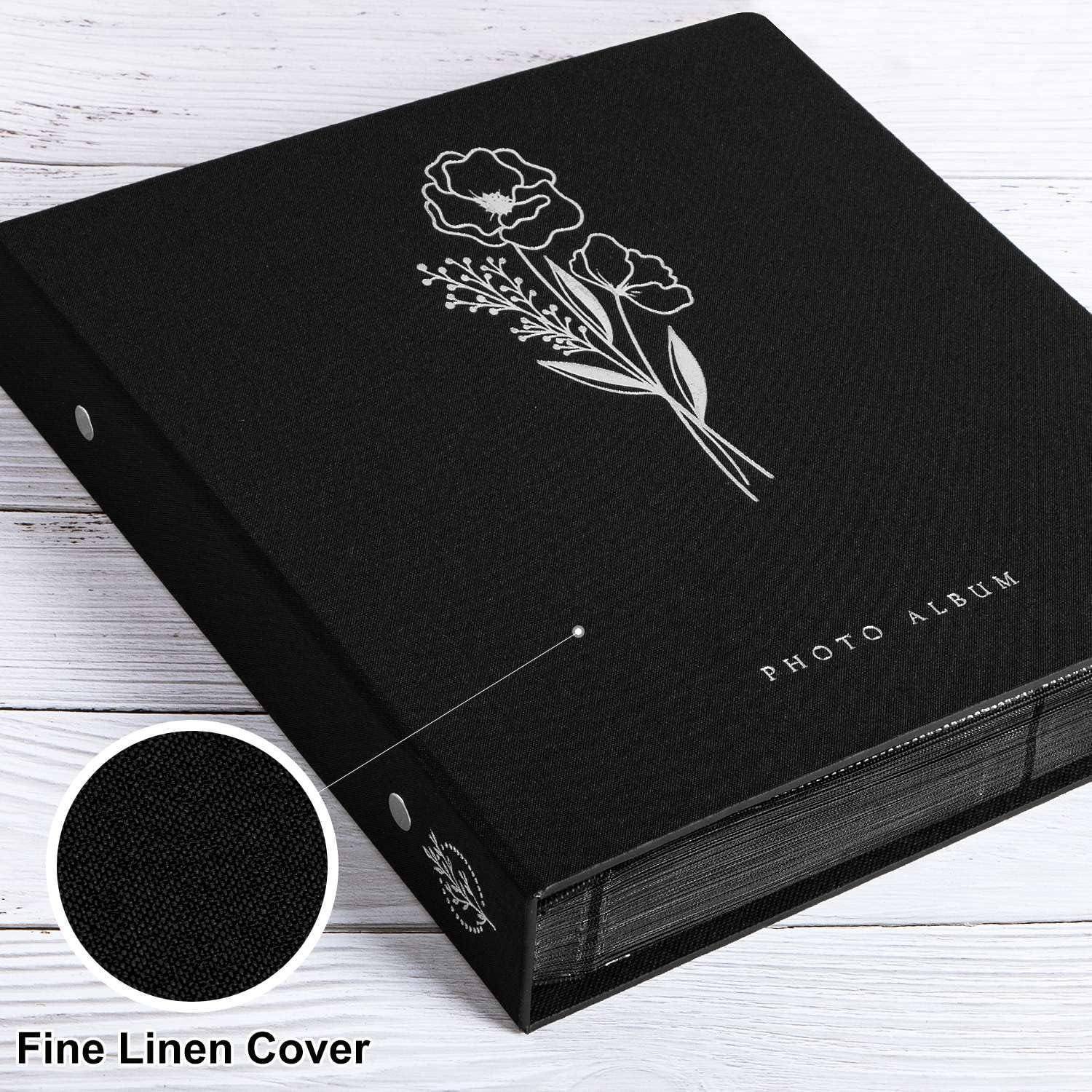 Schwarzes Fotoalbum mit einem Blumendesign auf dem Einband und den Worten 'Fotoalbum'. Einlage zeigt eine Nahaufnahme der feinen Leinwand-Einbandoberfläche.