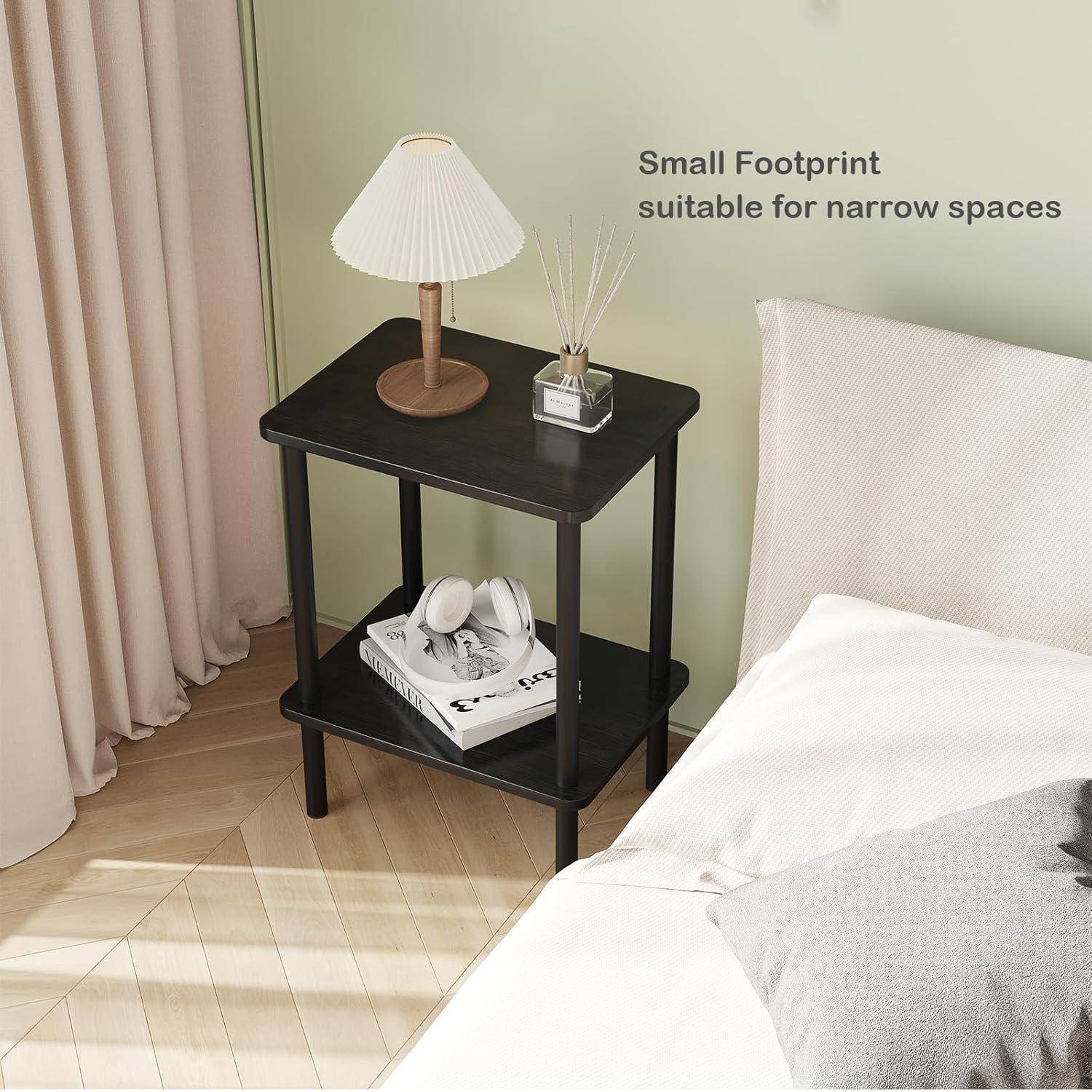 Ein kleiner schwarzer Beistelltisch mit einer Lampe, einer Pflanze und Büchern steht neben einem Bett in der Nähe von Vorhängen. Text lautet: ‚Kleiner Fußabdruck geeignet für schmale Räume.
