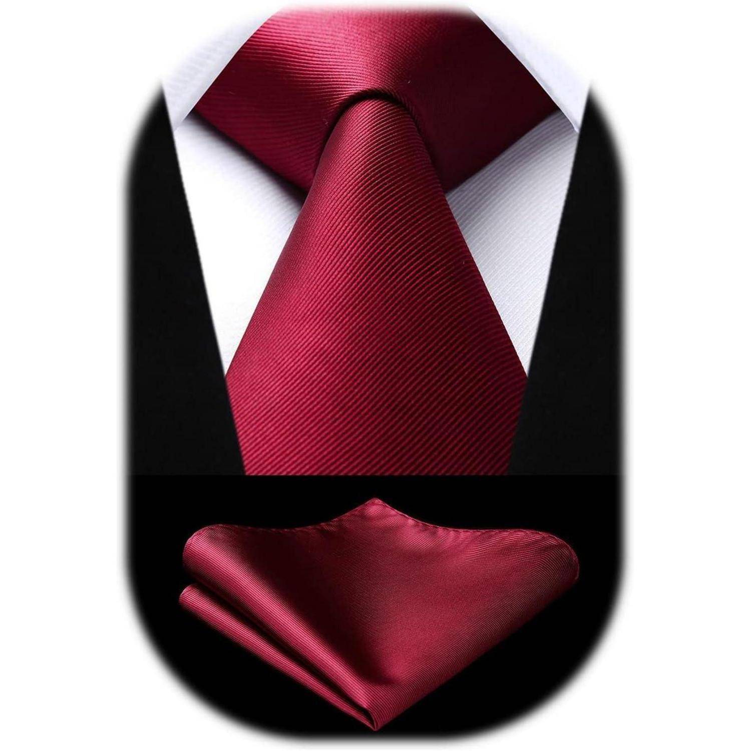 Eine rote Seidenkrawatte, kombiniert mit einem passenden Einstecktuch, ist vor einem weißen Hemd und einem schwarzen Anzug drapiert und veranschaulicht formelle Kleidung.