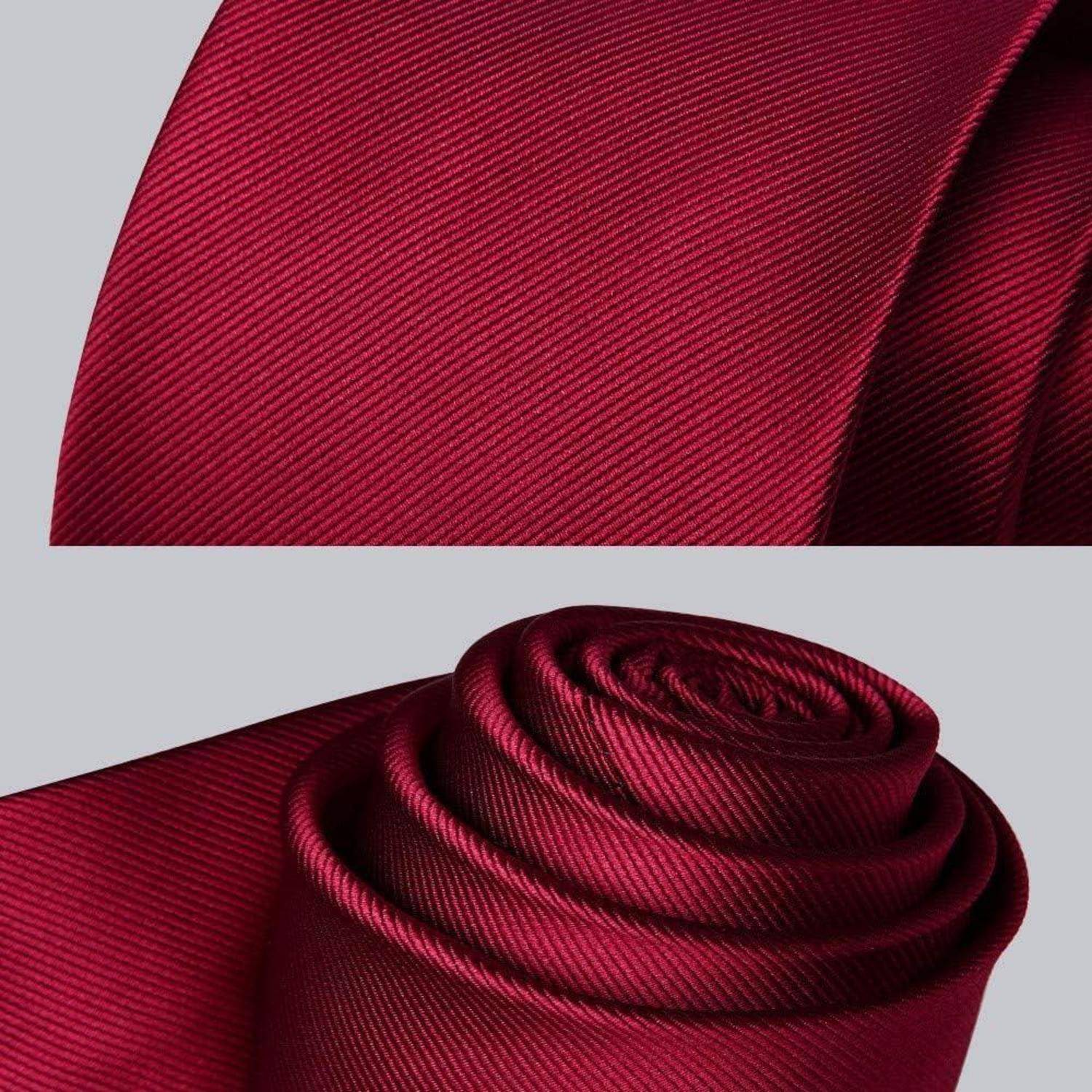 Eine Nahaufnahme einer gerollten, satten roten Krawatte mit einer dezenten diagonalen Streifenstruktur, die Eleganz und formelle Kleidung andeutet.