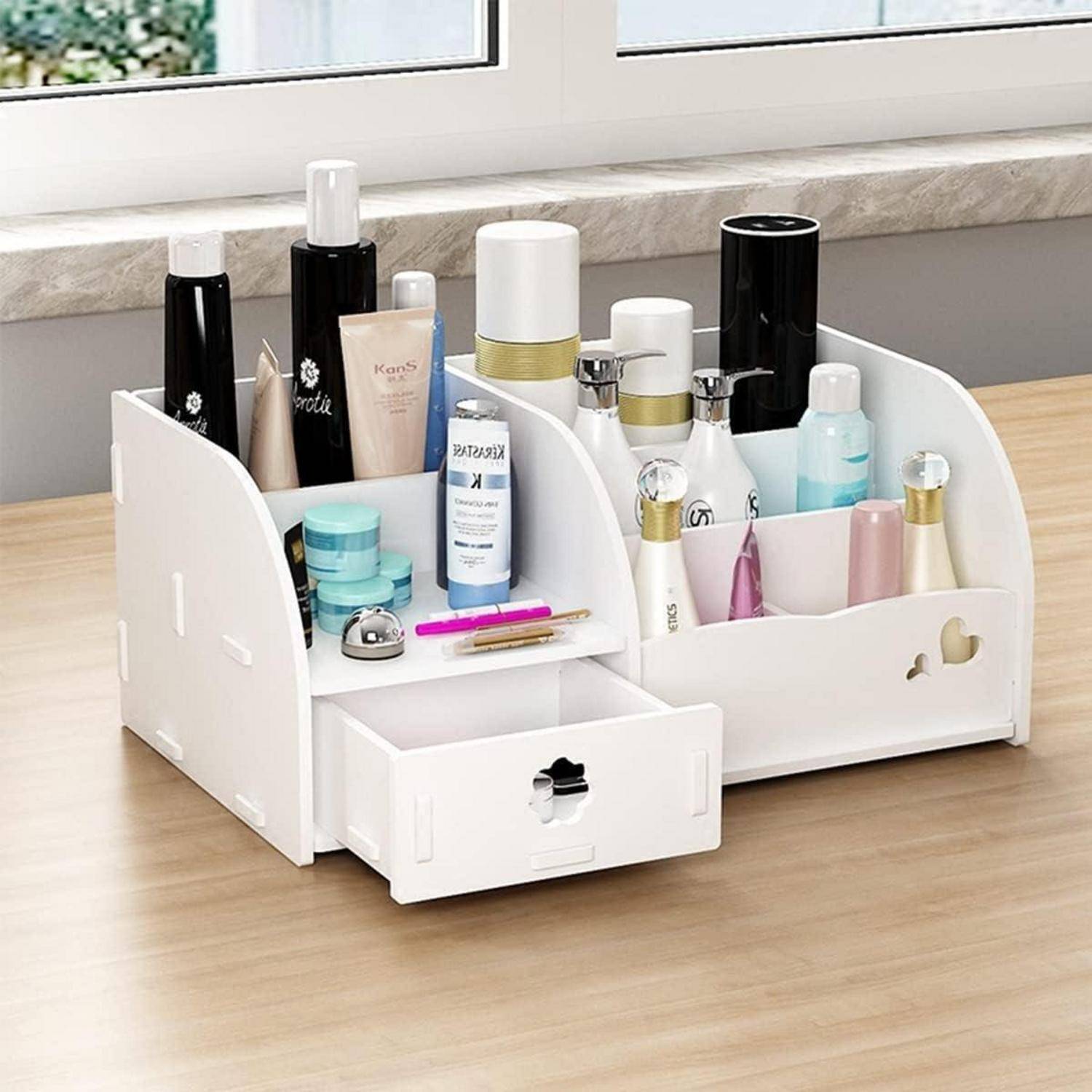 Ein weißer Kosmetikorganizer auf einem Holztisch, der verschiedene Hautpflegeflaschen, Gläser und Make-up-Artikel enthält, mit einer geöffneten Schublade.