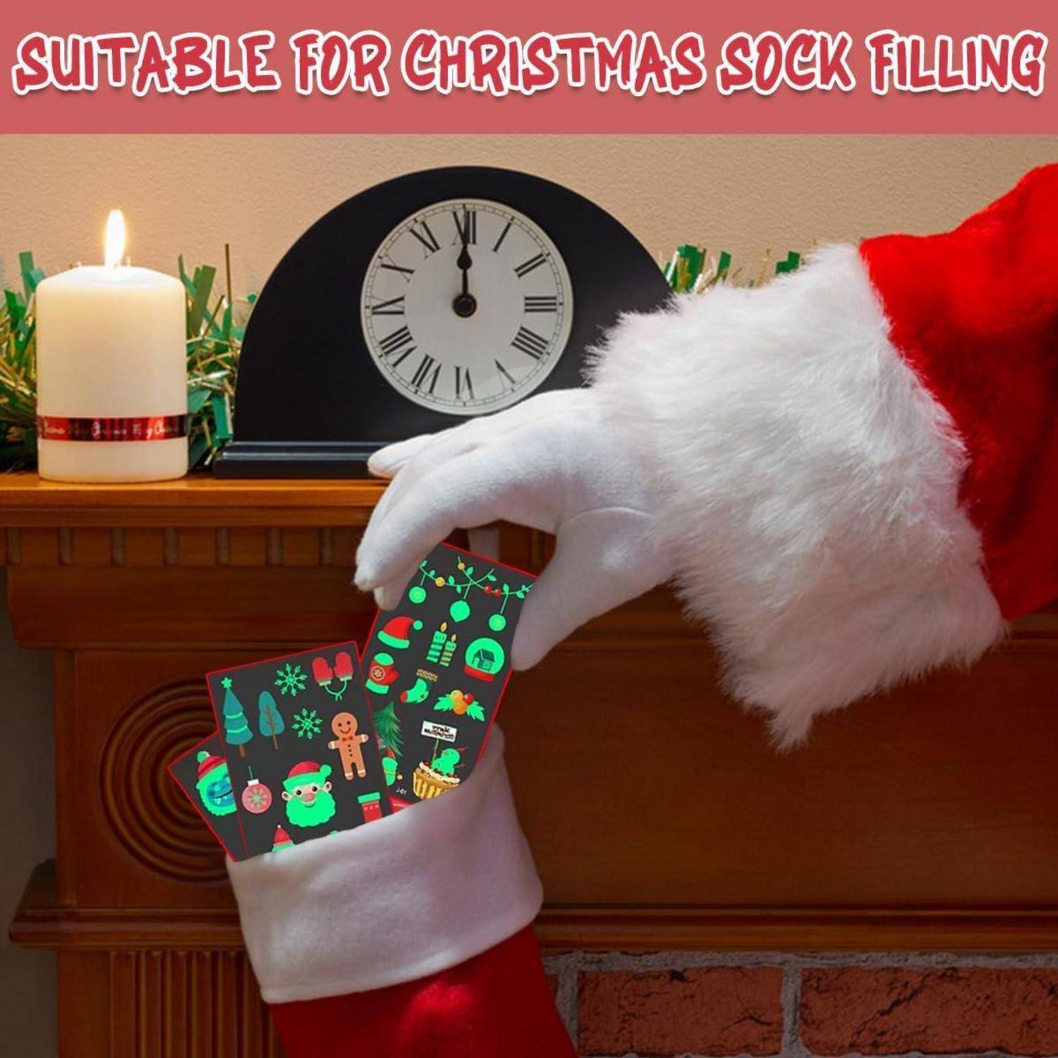 Eine Hand in einem Weihnachtsmannkostüm legt bunte Schokoladen in einen Weihnachtsstrumpf neben einem Kamin mit einer Kerze und einer Uhr. Text lautet: 