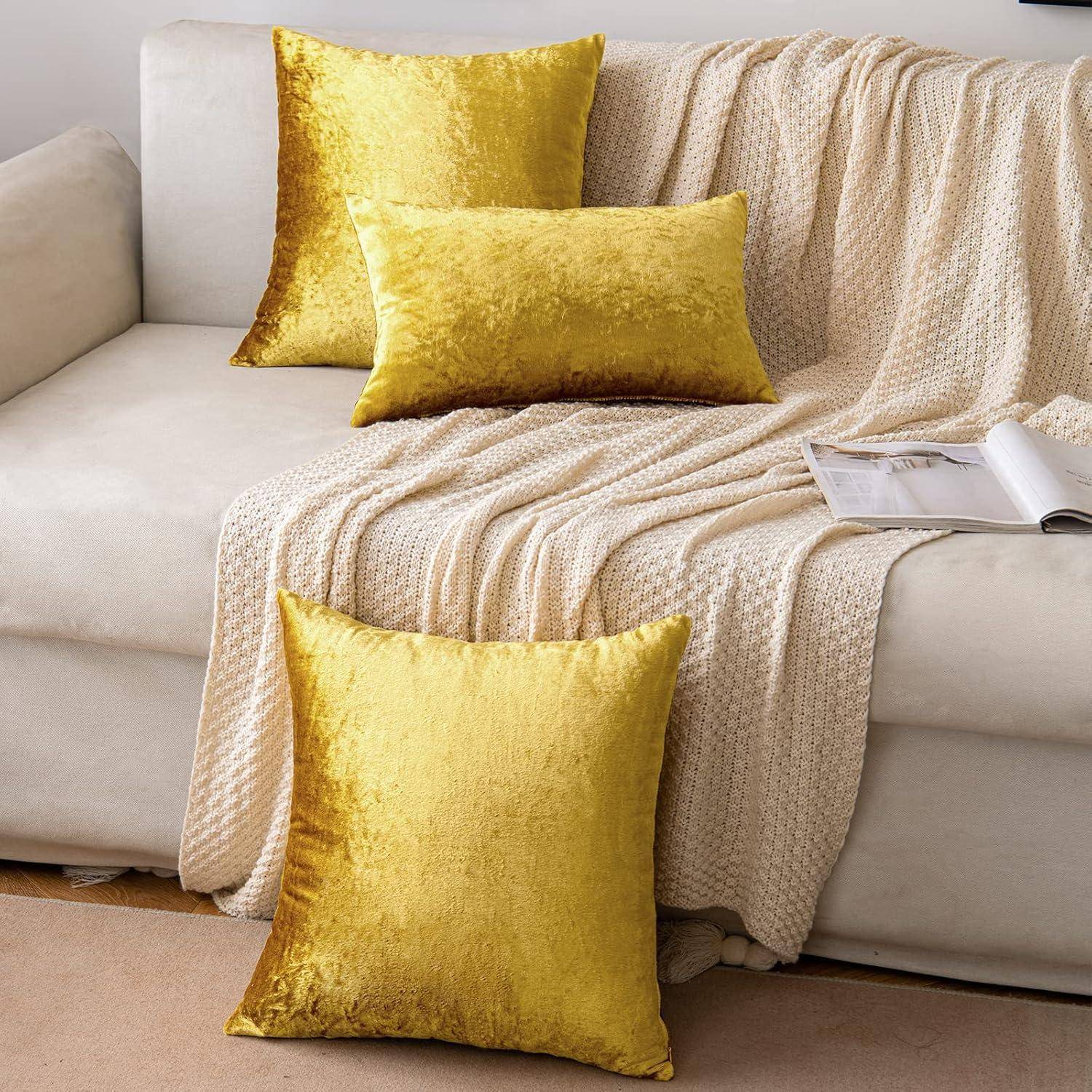 Ein beige Sofa, geschmückt mit einer leichten gestrickten Decke und drei golden-gelben Samtlisenen, die ordentlich darauf drapiert sind.