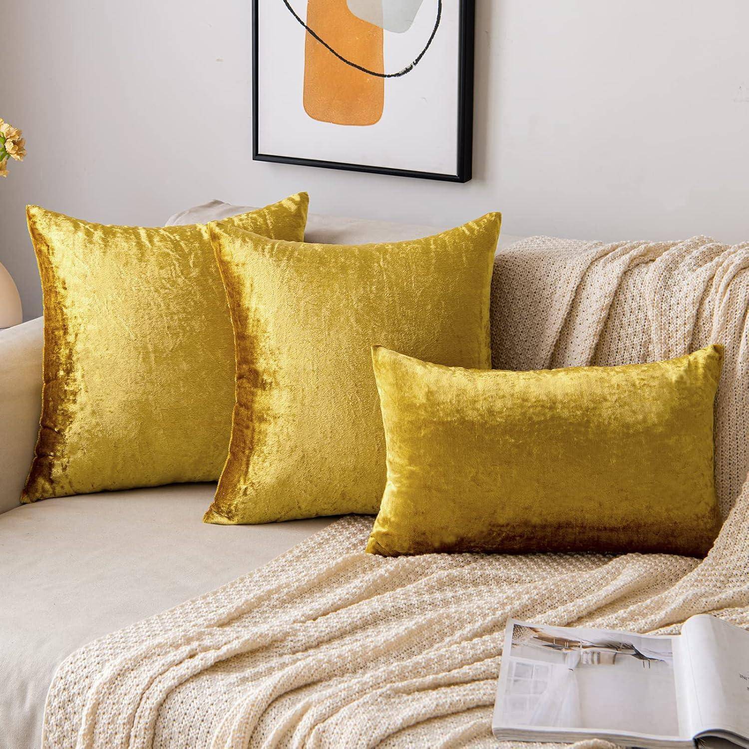 Ein gemütliches Wohnzimmer mit einem beigen Sofa, geschmückt mit drei goldenen Plüschkissen und einer strukturierten Decke, unter einem modernen gerahmten Kunstwerk.