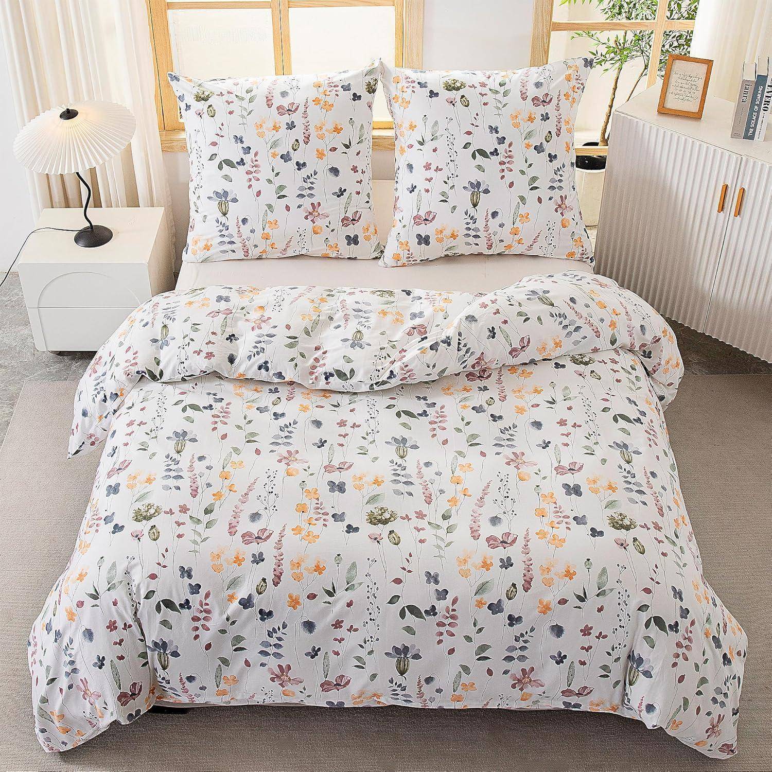 Ein ordentlich gemachtes Bett mit Bettwäsche im Blumenmuster, zwei passenden Kissen, einem weißen Nachttisch mit einer Lampe und einem Holzschrank daneben.