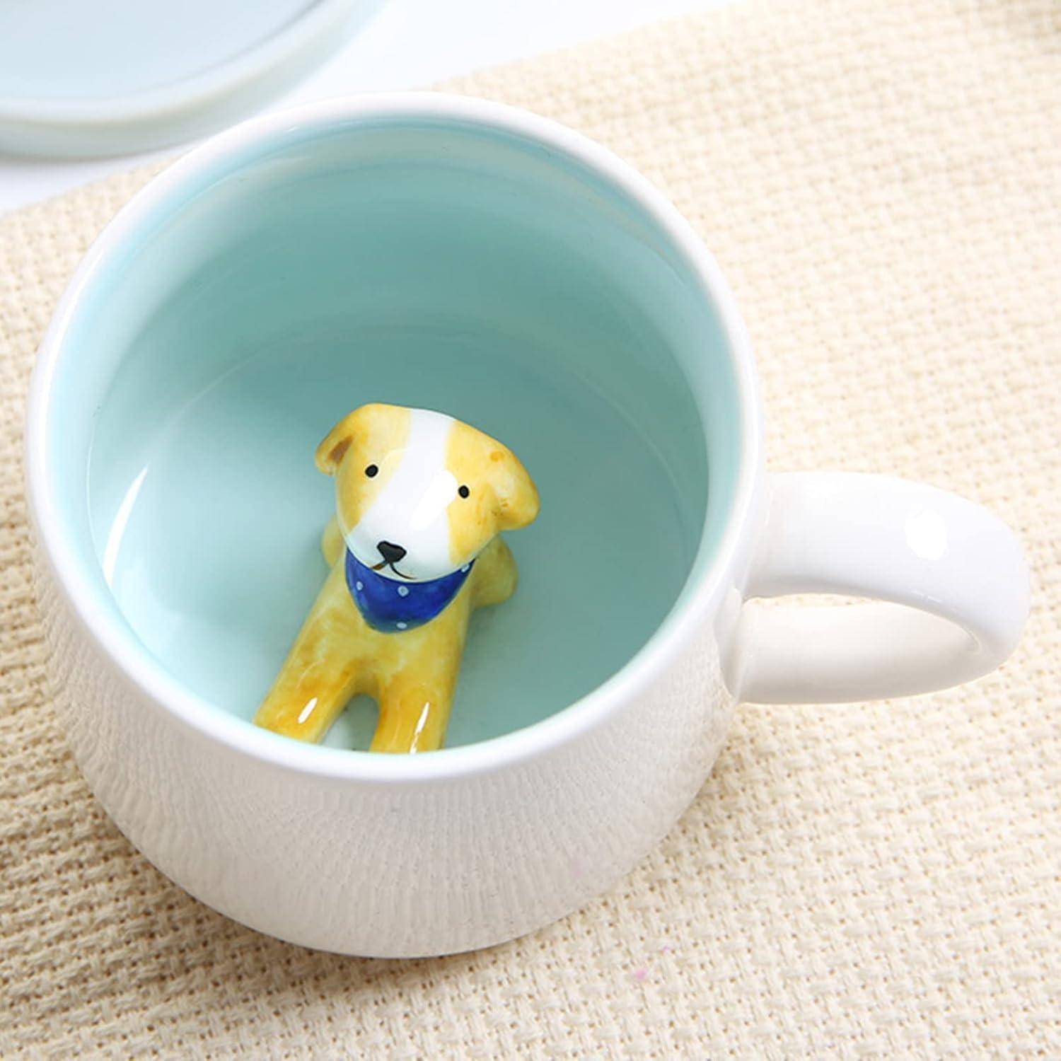Eine Keramiktasse mit hellblauem Innenraum zeigt eine 3D-Figur eines kleinen, gelben Hundes am Boden, der einen blauen Schal trägt.