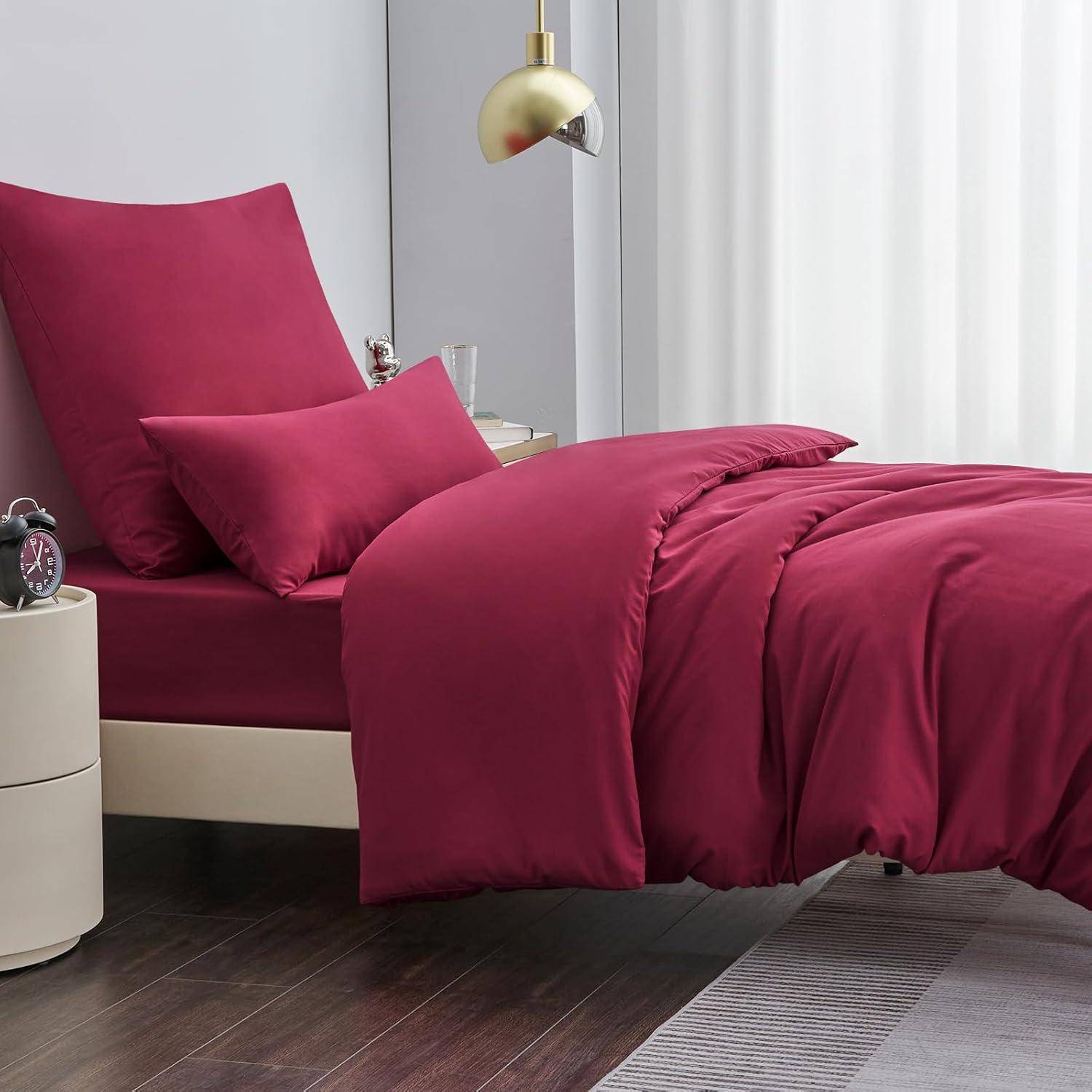 Ein Schlafzimmer mit einem Bett, das mit roter Bettwäsche und Kissen bezogen ist, ein Nachttisch mit zwei Schubladen und Dekorationsgegenständen sowie eine goldene Deckenlampe.