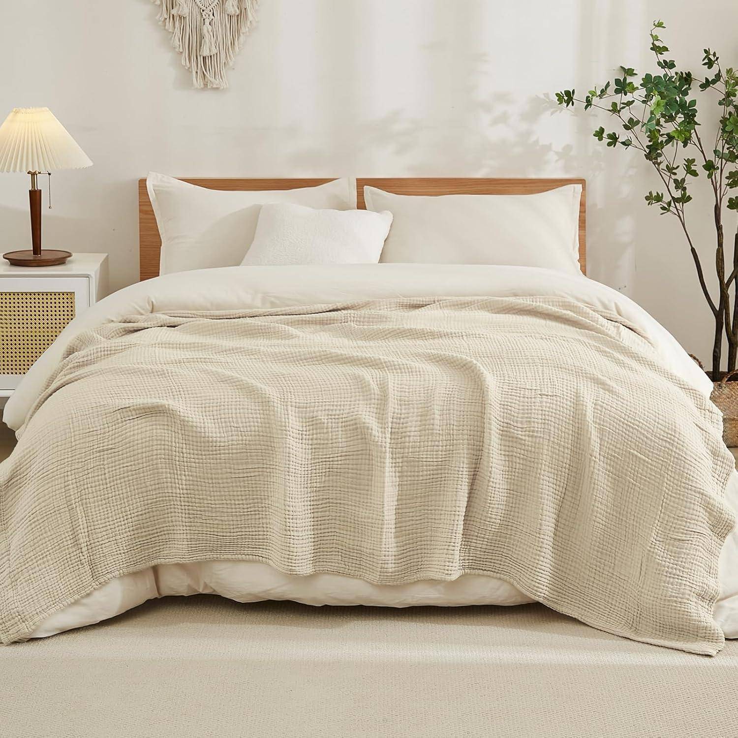 Ein ordentlich gemachtes Bett mit beigefarbener Bettwäsche und weißen Kissen, flankiert von einem Nachttisch mit einer Lampe und Pflanzen, deutet auf eine gemütliche Schlafzimmereinrichtung hin.