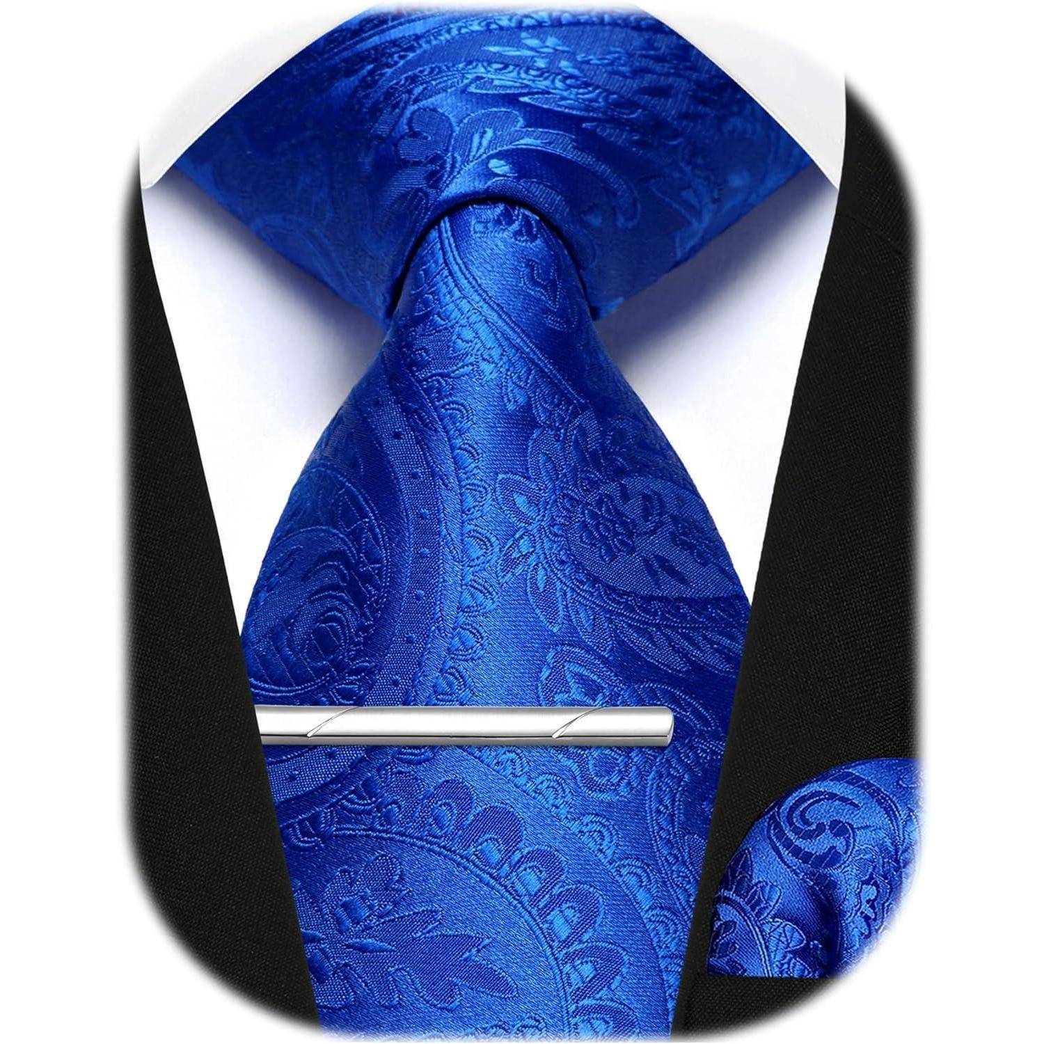 Eine Nahaufnahme einer blauen Krawatte mit Paisley-Muster und einer silbernen Krawattennadel, getragen unter einem schwarzen Sakko.