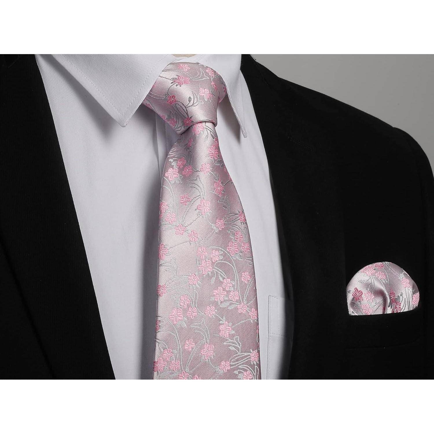 Eine Person, die einen schwarzen Anzug mit einem weißen Hemd trägt und eine rosa Krawatte mit Blumenmuster sowie ein passendes Einstecktuch präsentiert.