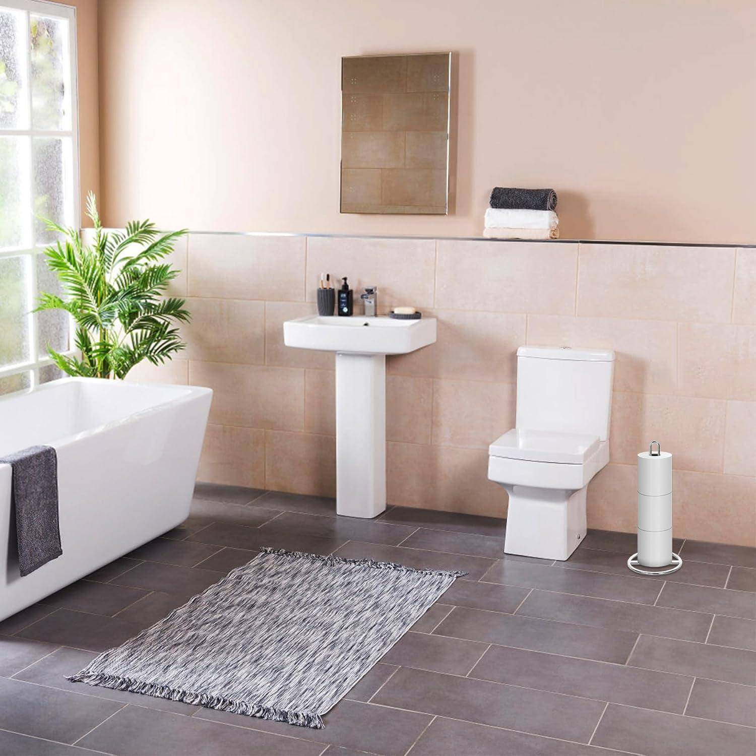 Modernes Badezimmer mit einer weißen Badewanne, einem Standwaschbecken und einer Toilette. Helle Fliesen und eine graue Bodenmatte ergänzen das natürliche Licht von einem Fenster.
