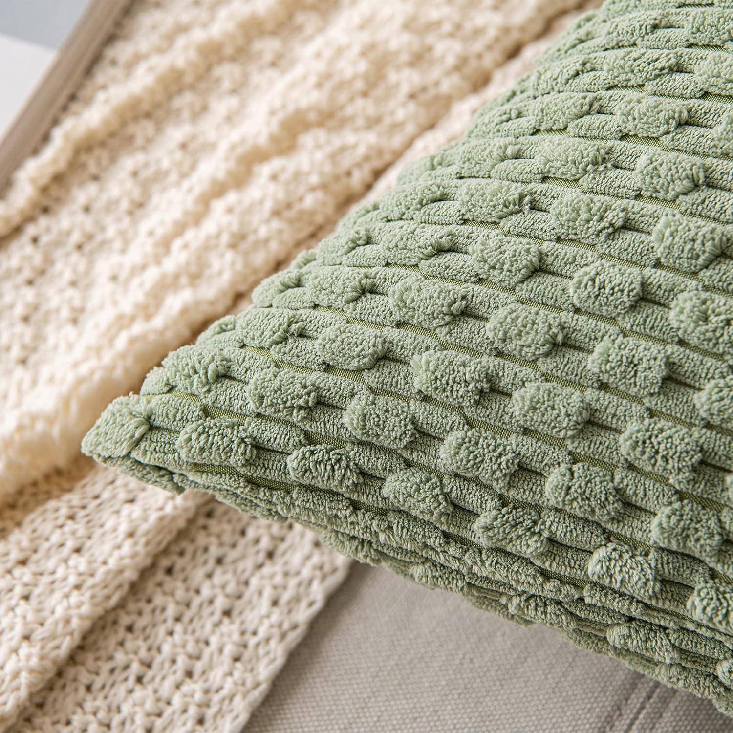 Ein strukturiertes grünes Kissen auf einer beigen gestrickten Decke.