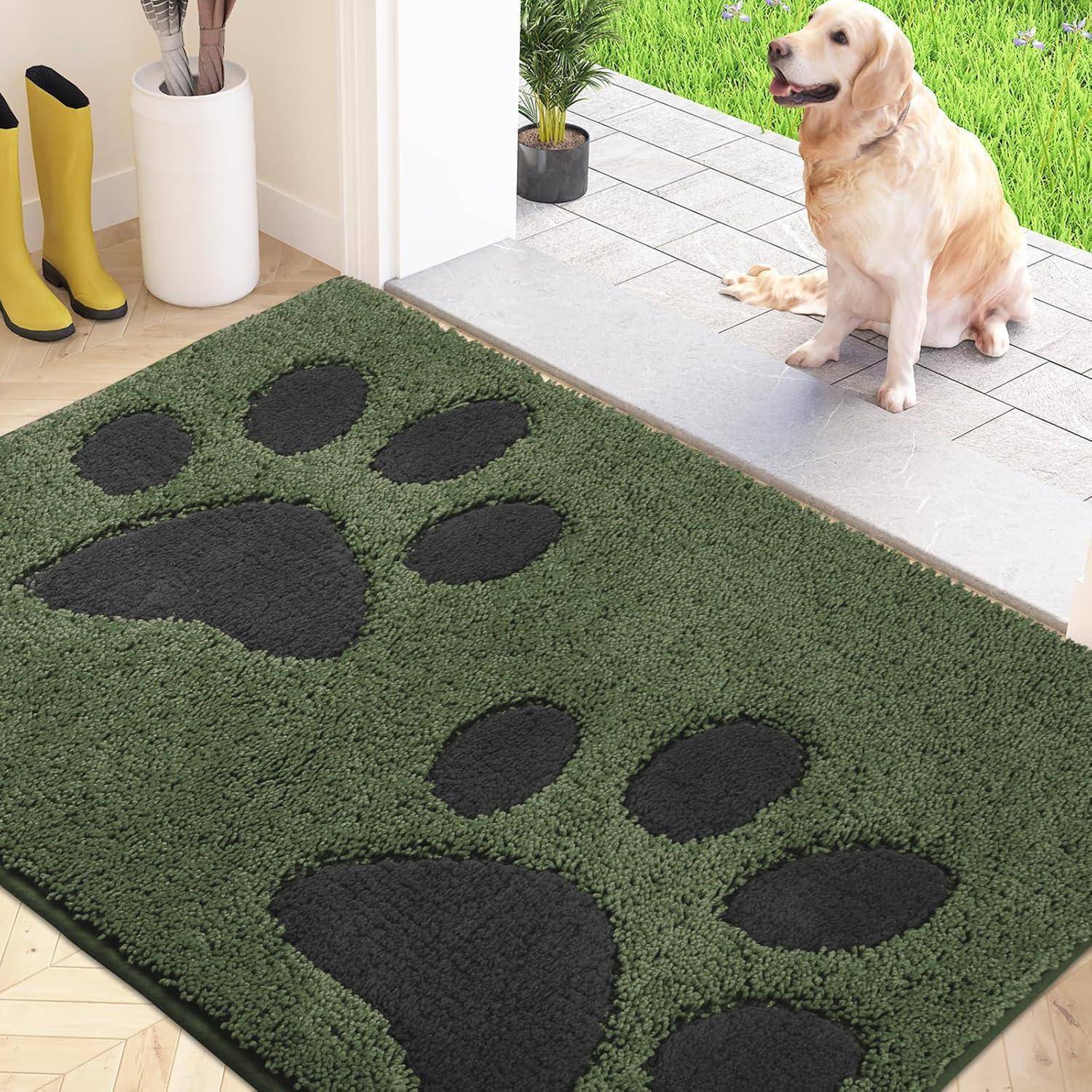 Eine flauschige grüne Matte mit schwarzen Pfotenabdruckmustern liegt im Türeingang. Ein Hund sitzt draußen auf der Terrasse, mit einem Rasenplatz im Blickfeld.