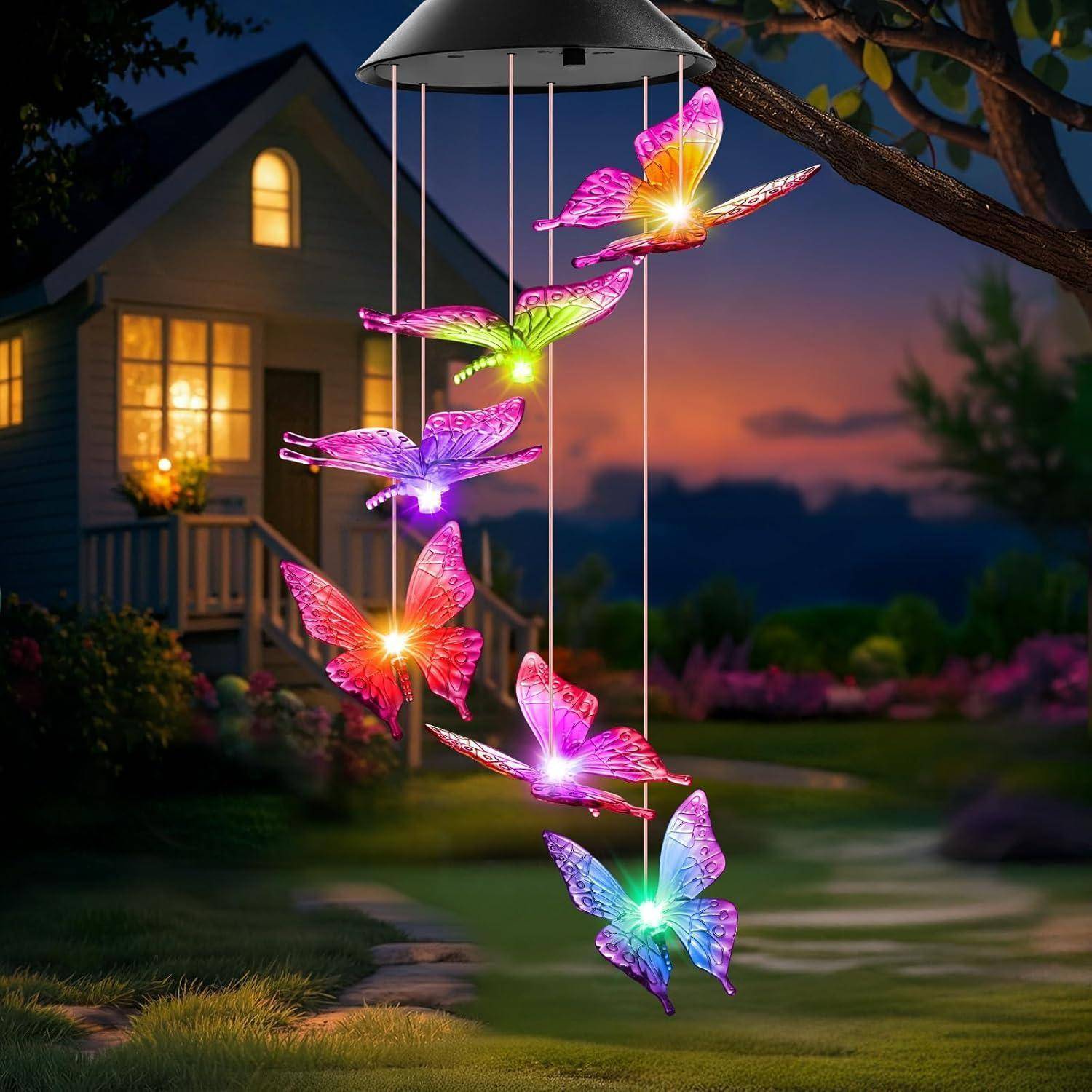 Solarbetriebenes Windspiel mit leuchtenden Schmetterlingen, die außerhalb eines Hauses in der Abenddämmerung hängen und den Gartenweg darunter beleuchten.