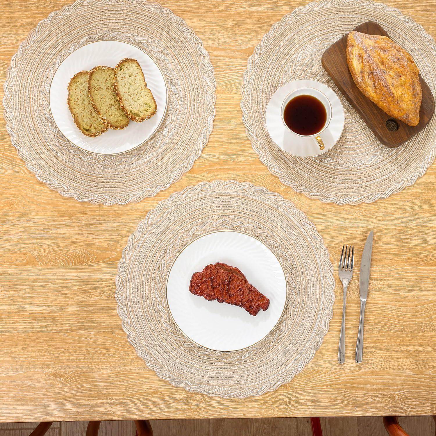 Eine Draufsicht eines Esstisches mit einer Tasse Kaffee, einem Brot auf einem Holzbrett, geschnittenem Kuchen auf einem Teller und einem Stück rotem Fleisch auf einem Platzdeckchen.