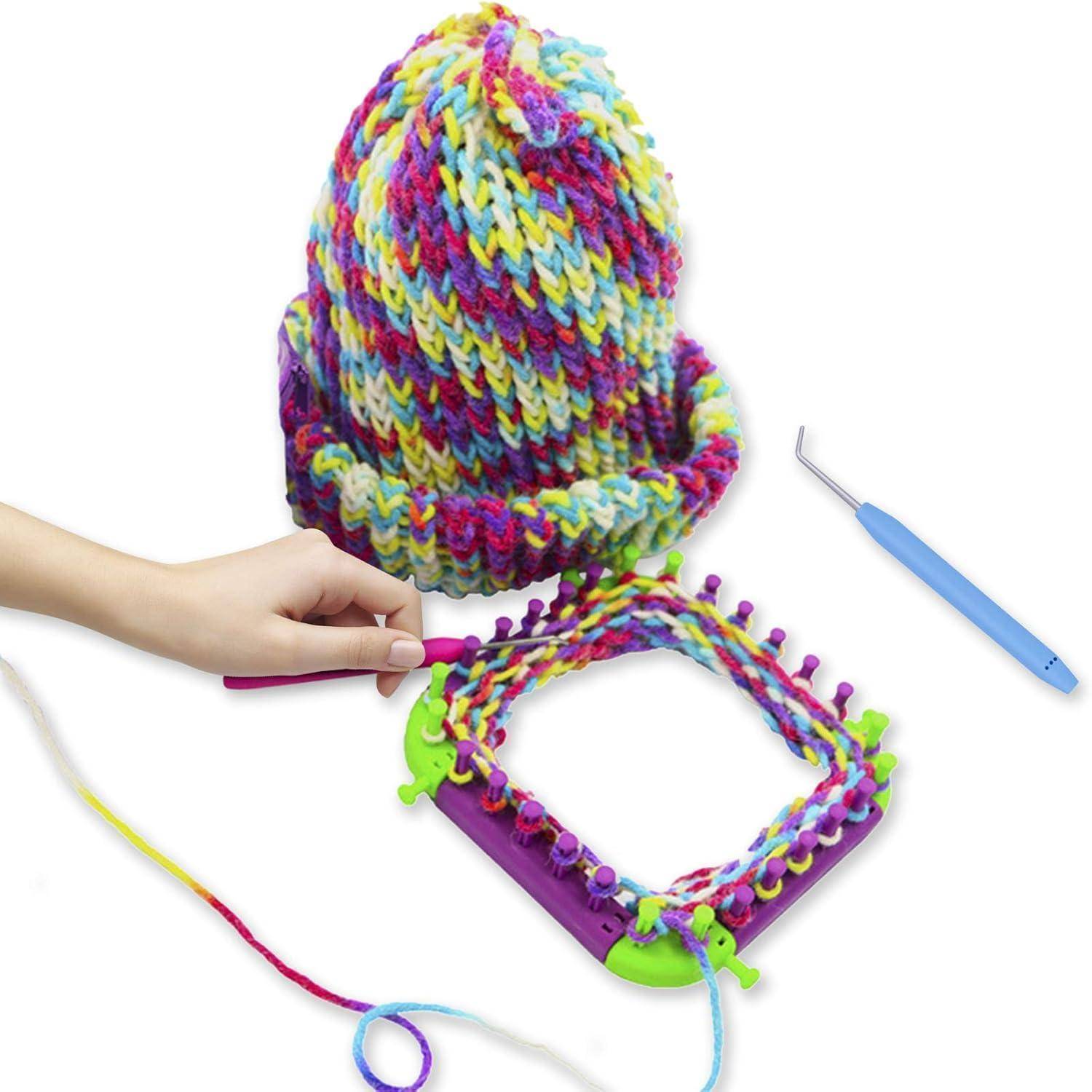 Eine Hand verwendet einen Strickrahmen mit mehrfarbigem Garn und stellt eine Mütze her. Ein Häkelnadel und die fertige Mütze sind in der Nähe sichtbar.