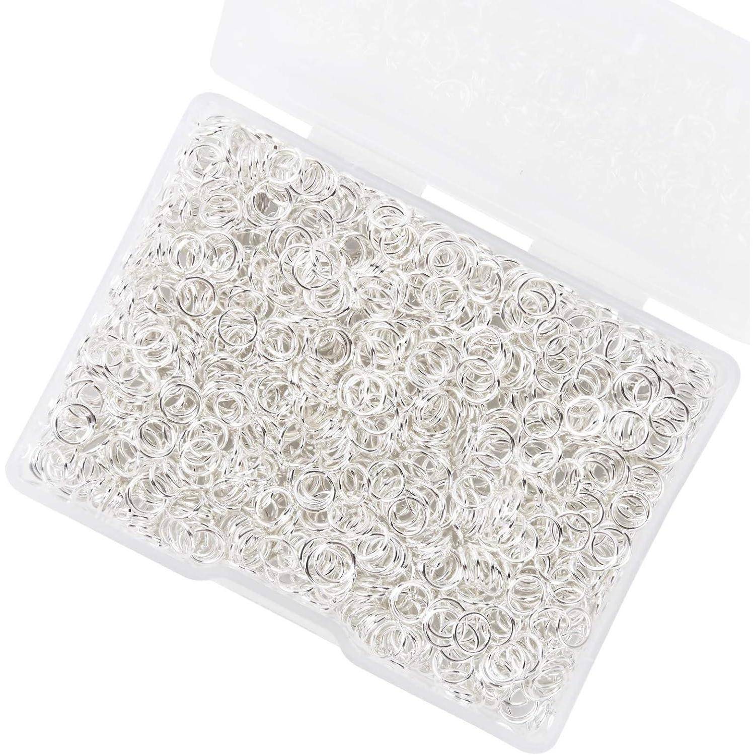 Eine durchsichtige Plastikbox gefüllt mit zahlreichen kleinen silbernen Biegeringen, die zum Schmuckherstellen verwendet werden.
