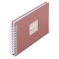 Ein spiralgebundenes Notizbuch mit rosa Einband, das ein rechteckiges Fenster mit dem Wort ‚Glück' zeigt.