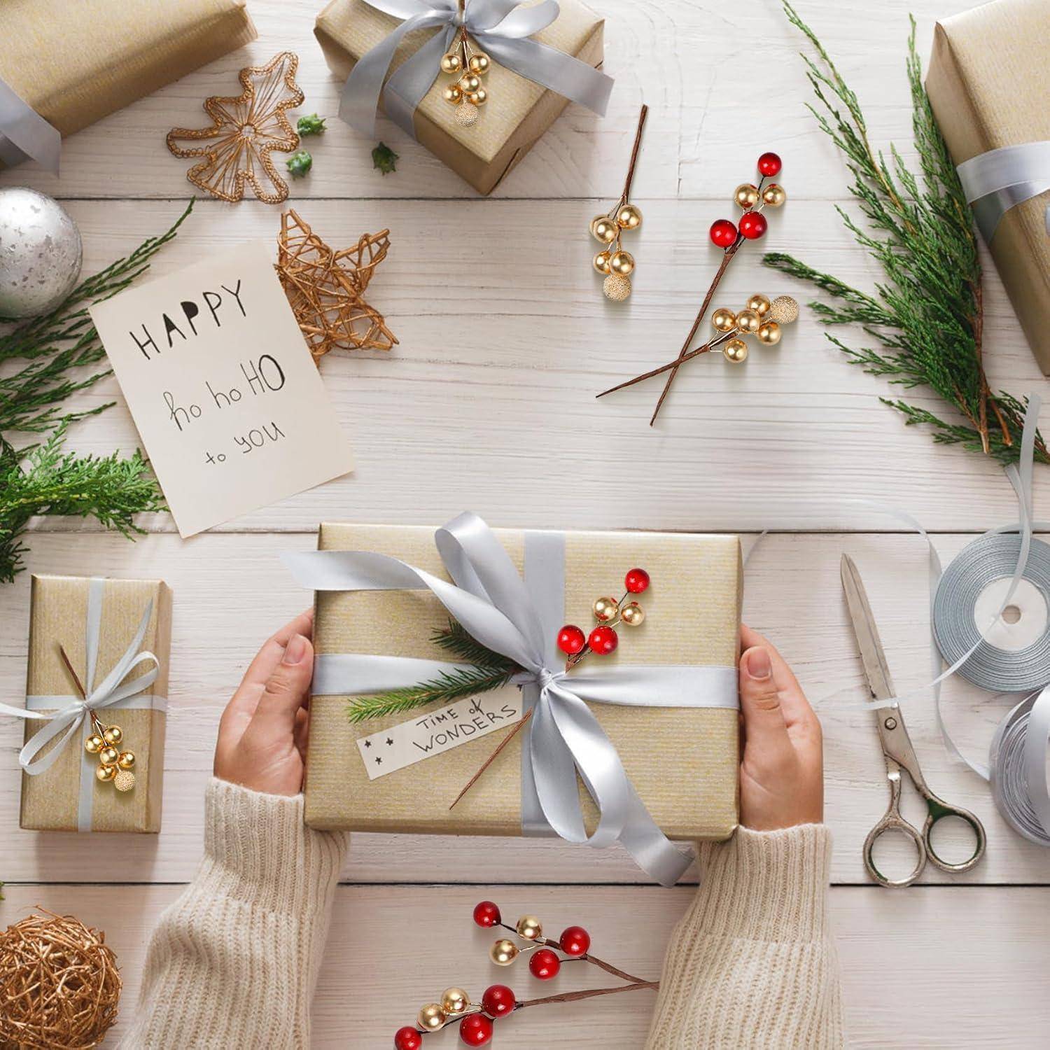 Eine Person hält ein eingepacktes Geschenk mit einer silbernen Schleife. Weitere Geschenke, Verpackungsmaterialien und eine festliche Karte mit der Aufschrift 