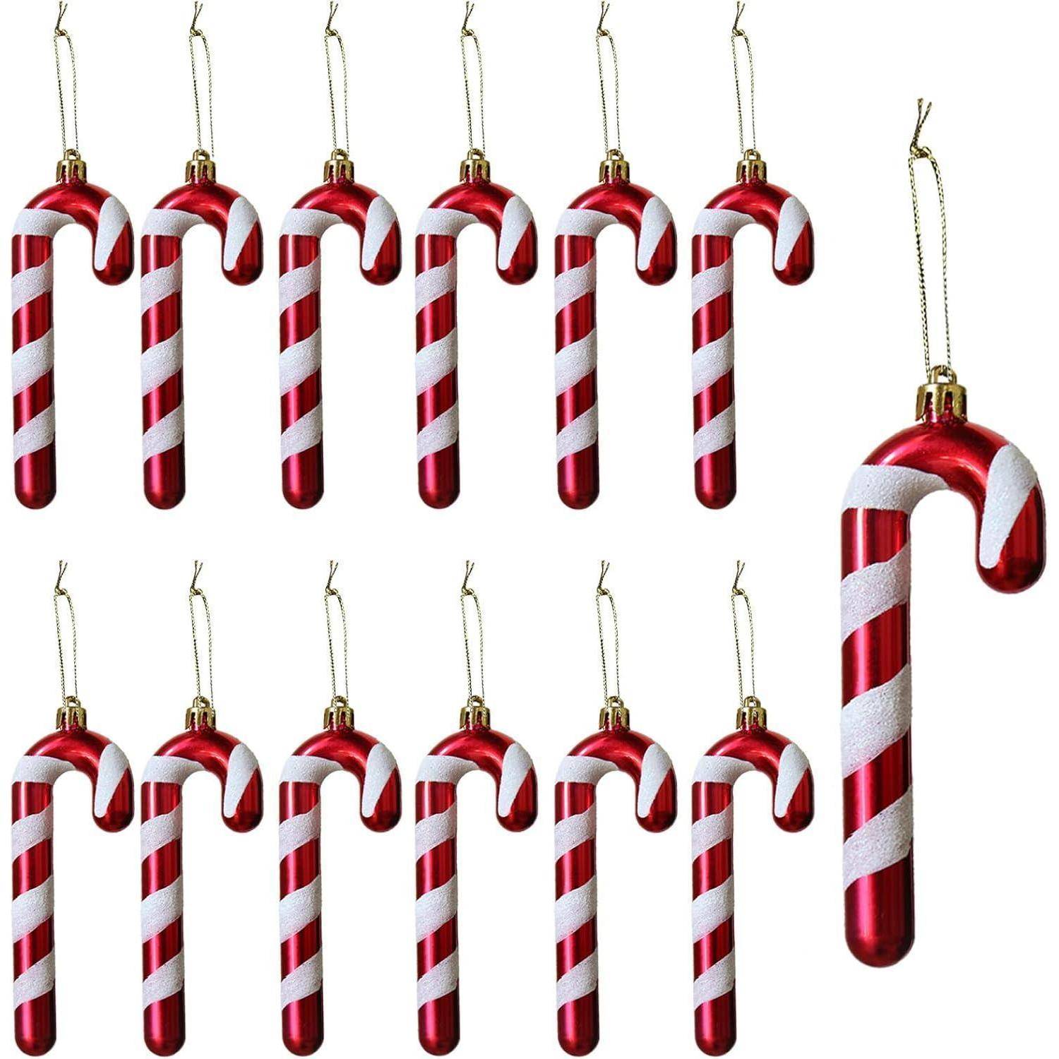 Zwölf rot-weiß gestreifte Zuckerstangen-Christbaumanhänger mit goldenen Aufhängern, in Reihen angeordnet.