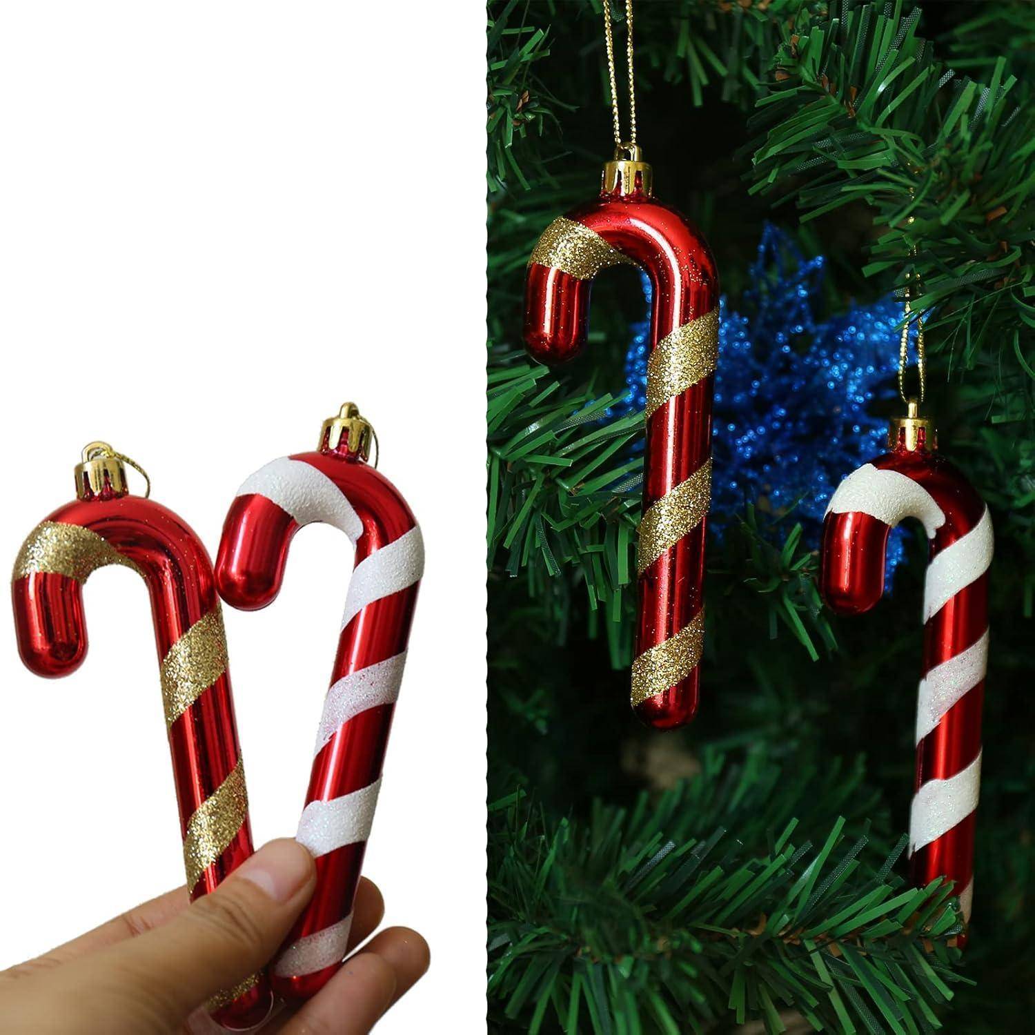Zwei rot-weiße Zuckerstangen-Christbaumanhänger mit goldenen Streifen, die in der Hand gehalten werden, mit ähnlichen Ornamenten, die im Hintergrund am Weihnachtsbaum hängen.